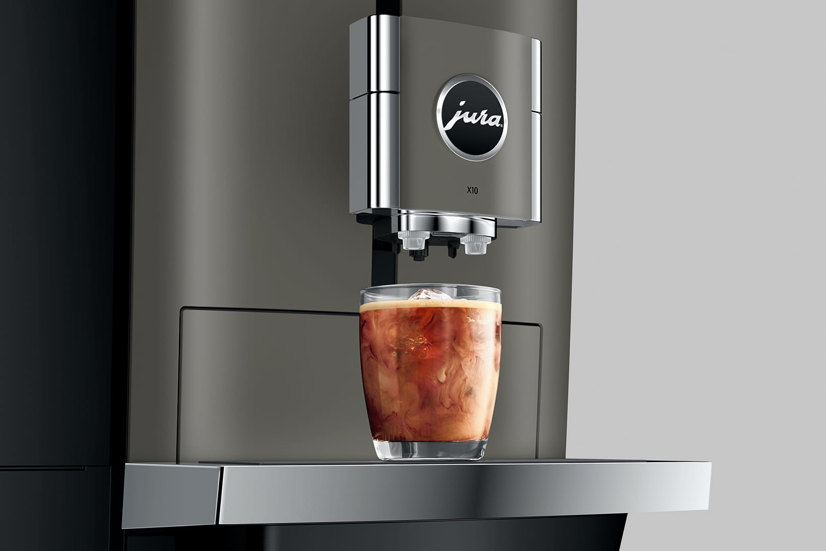 Macchina da caffè prepara bevanda in bicchiere con ghiaccio e vortici di latte.