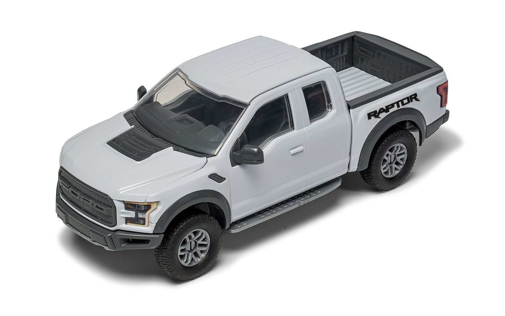 Biały pick-up zabawka z napisem 'RAPTOR' na klapie bagażnika.