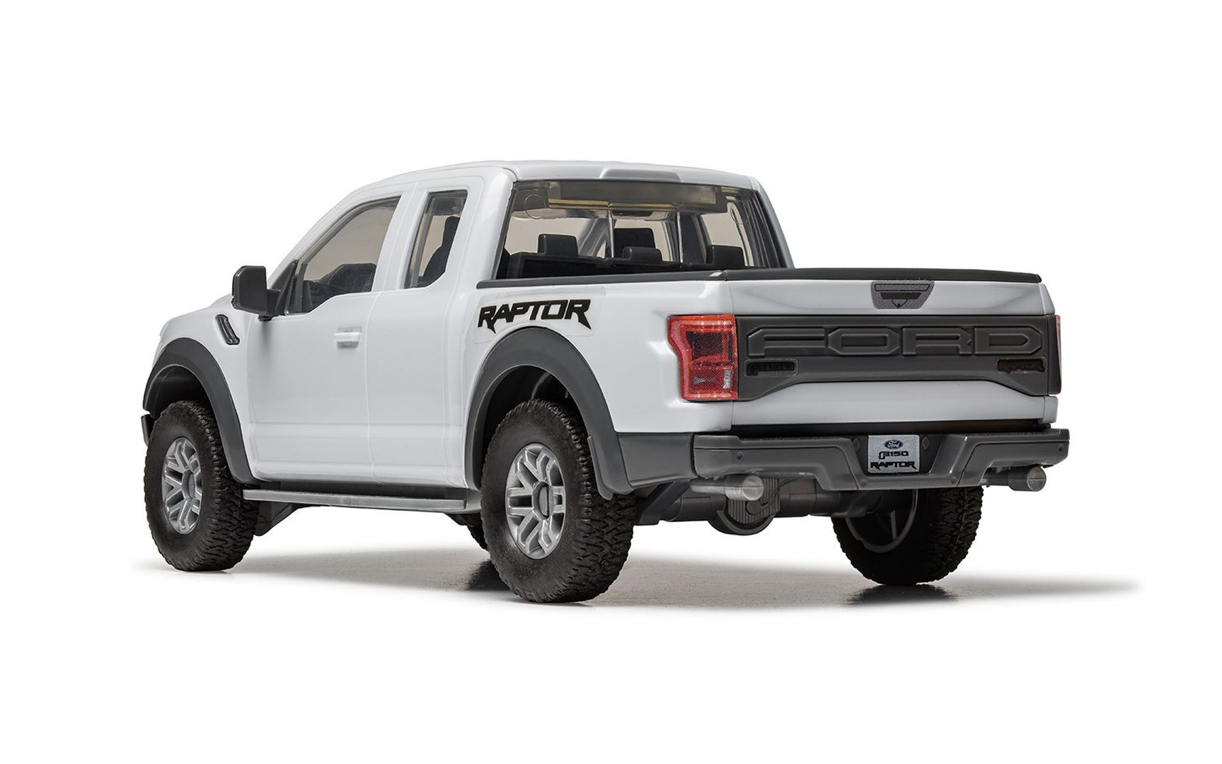 Biały Ford F-150 Raptor jest pokazany z widoku z tyłu 3/4 na białym tle.