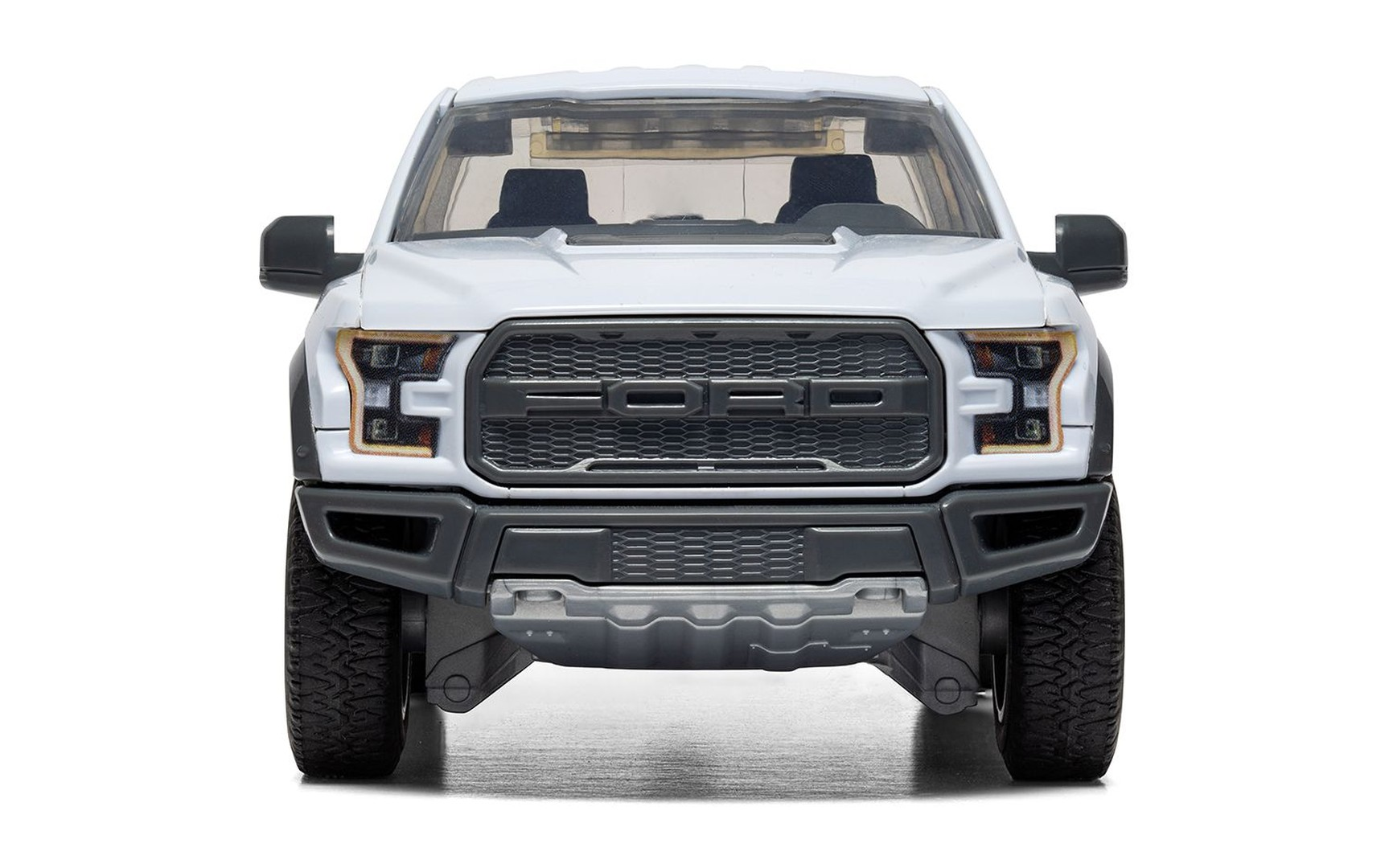 Biały pickup Ford Raptor widziany od przodu, z czarnym grillem i reflektorami.