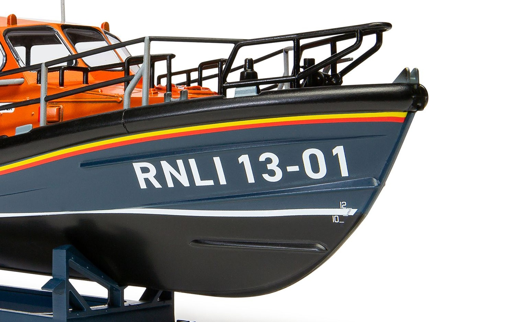 Statek ratowniczy z oznaczeniem RNLI 13-01 spoczywa na stojaku na białym tle.