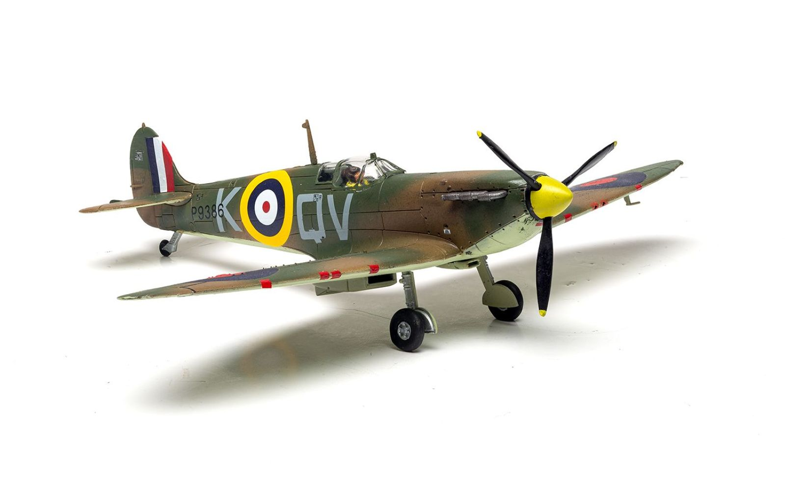 Zielono-brązowy model Spitfire z brytyjskimi oznaczeniami.