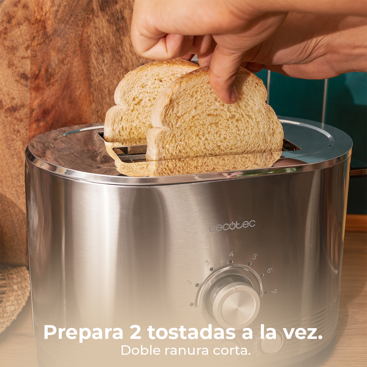 Eine Hand legt zwei Toastbrotscheiben in einen silbernen Toaster mit zwei Schlitzen.