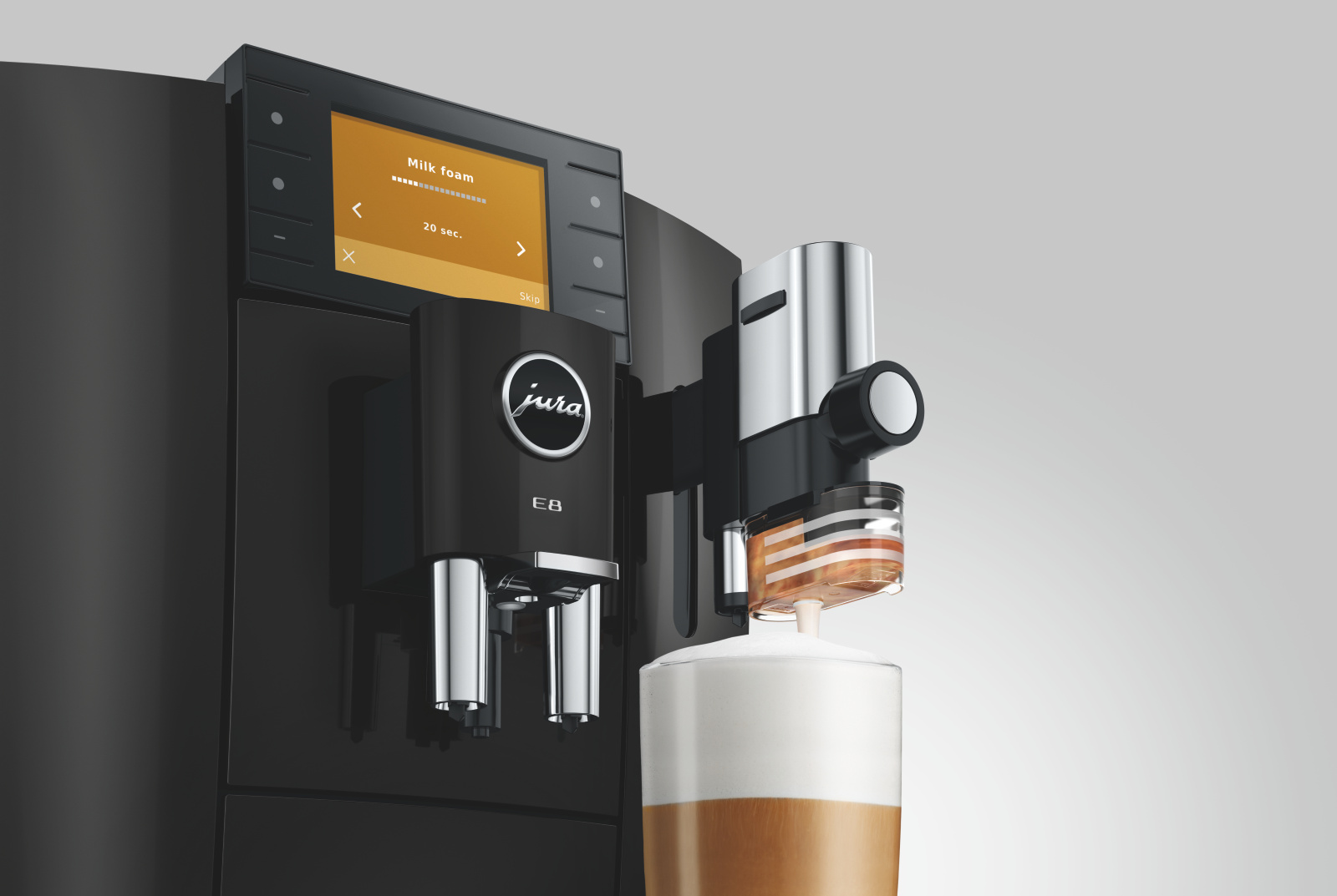 Una macchina da caffè Jura E8 nera monta il latte in un bicchiere.