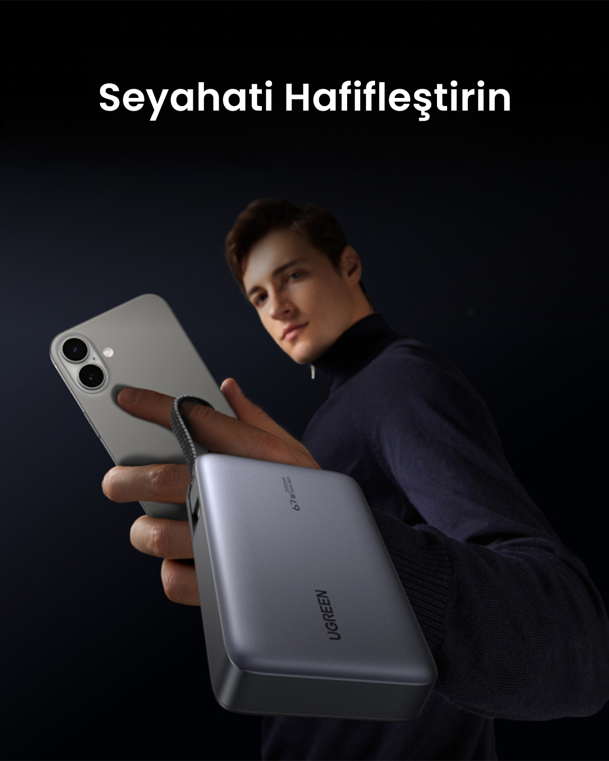 Mężczyzna trzyma smartfon i powerbank w ciemnym otoczeniu.