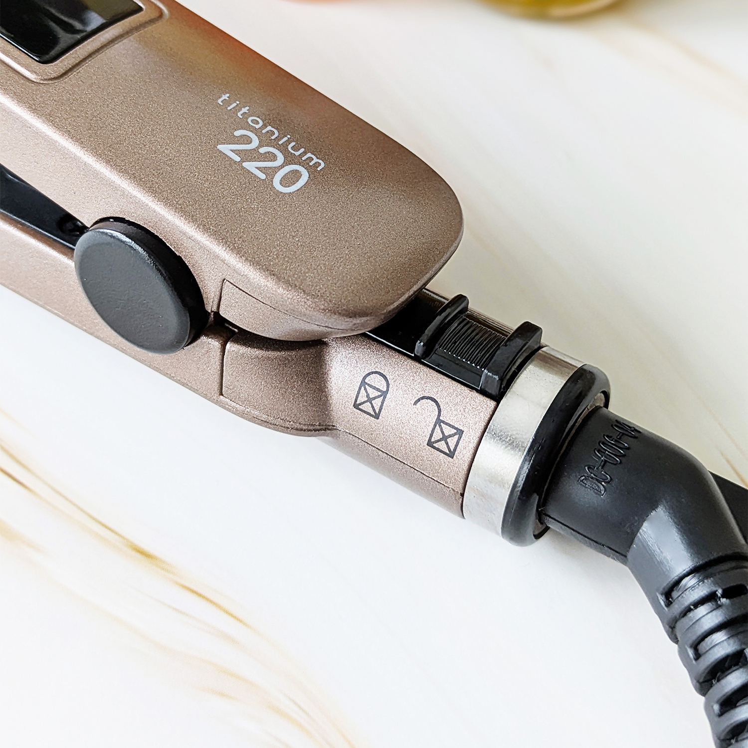 Un cepillo alisador de cabello bronce con texto "titanium 220".