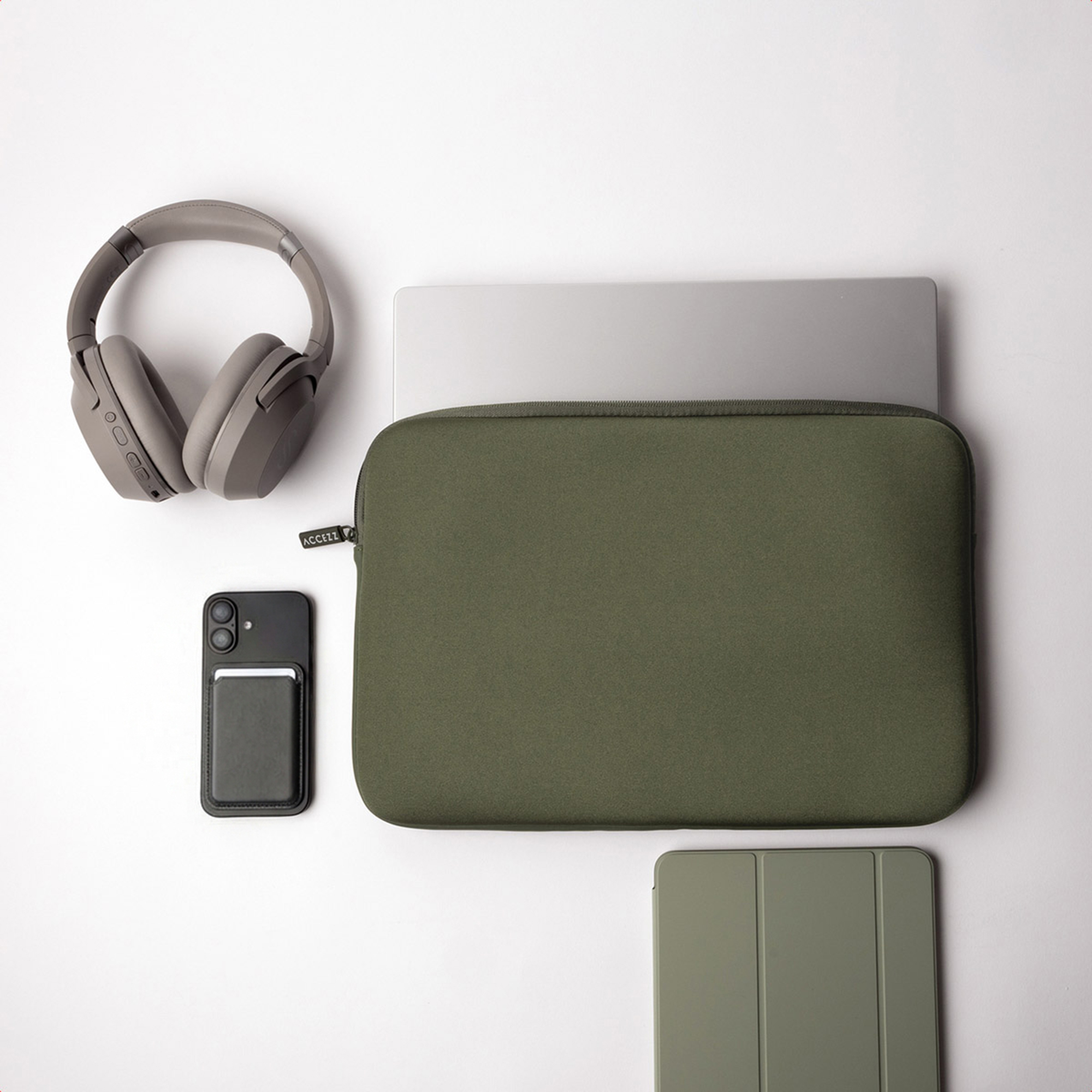 Gray headphones, dark phone with card holder, green laptop sleeve, and green tablet stand.