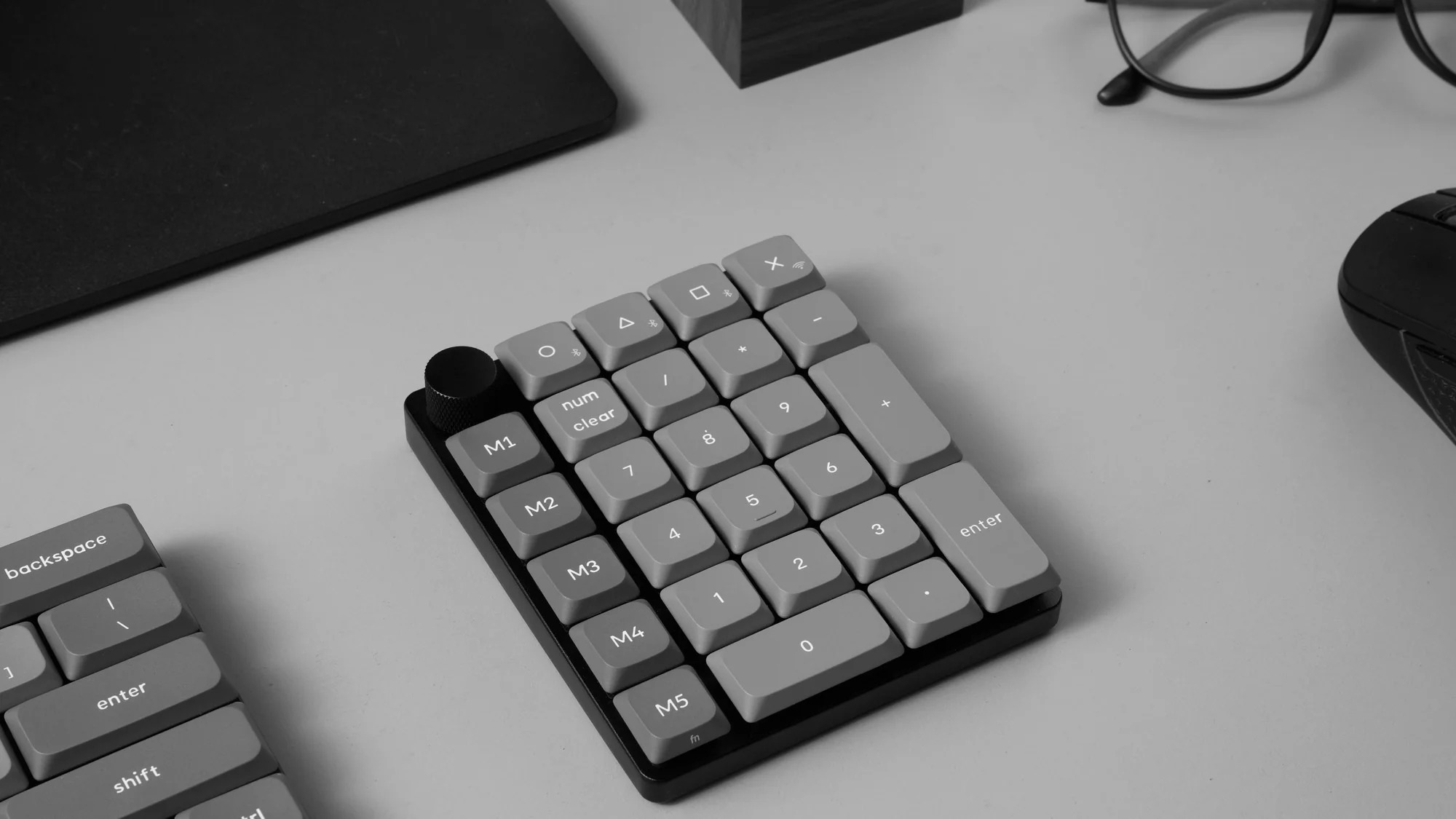 Szara klawiatura numeryczna, mysz i okulary na biurku.