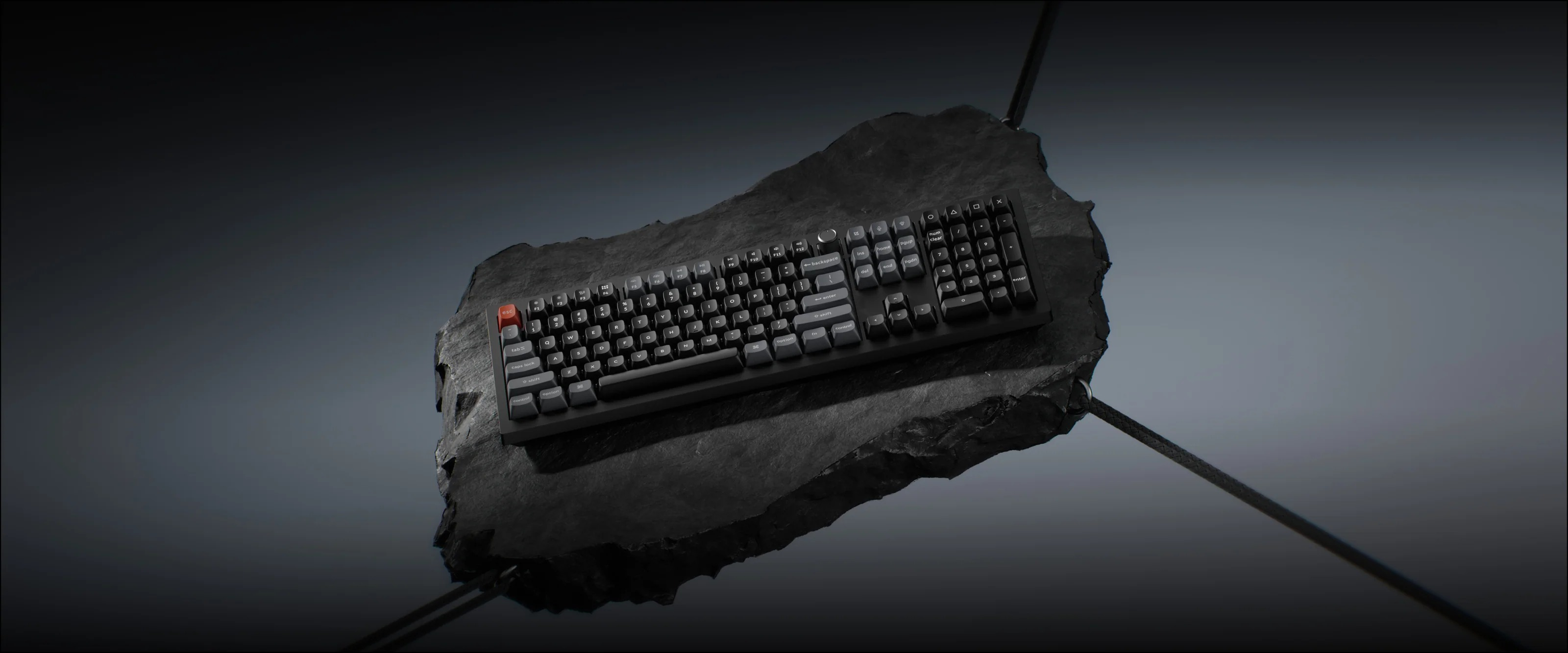 Czarna klawiatura z pomarańczowym klawiszem ESC na kamieniu.