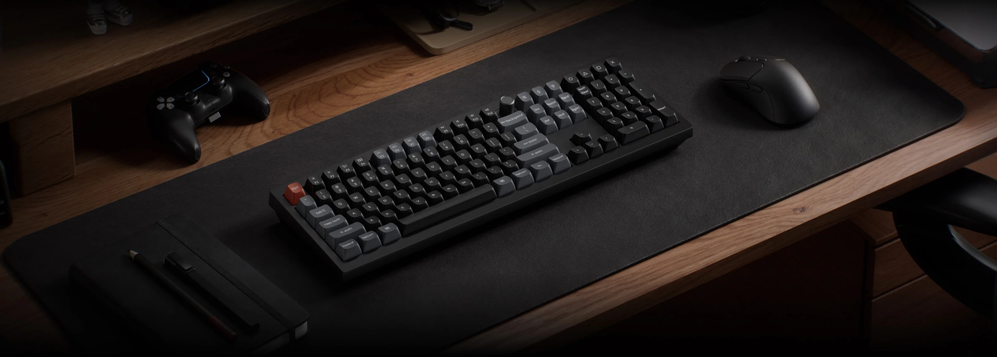 Ciemne biurko z klawiaturą, myszką, padem i notatnikiem.