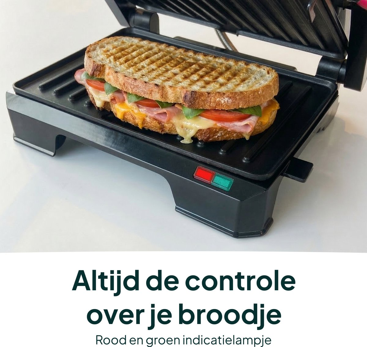 A grilled sandwich with ham, cheese, and tomato in an open sandwich maker.