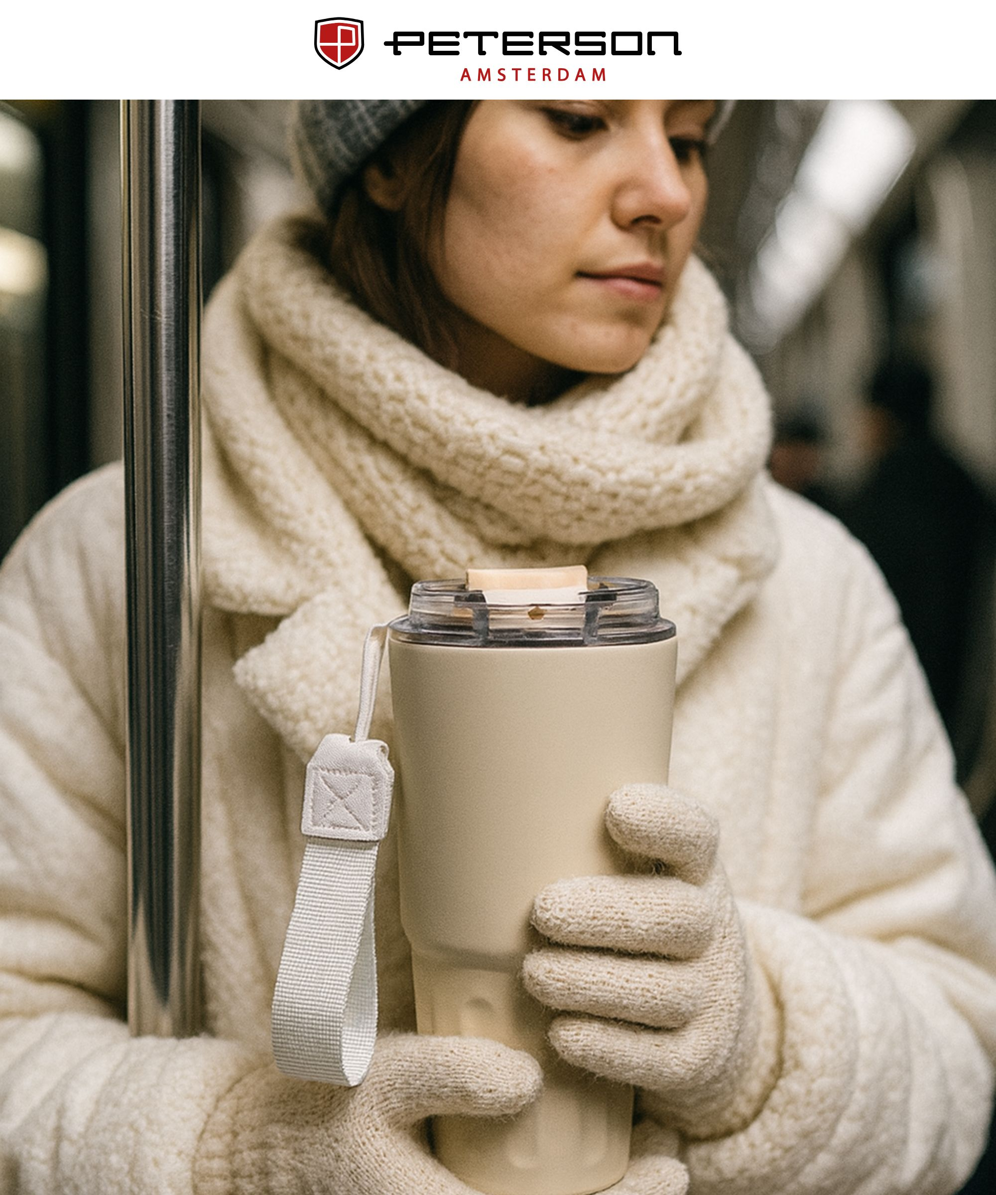 Kobieta w zimowych ubraniach trzyma beżowy kubek w metrze.