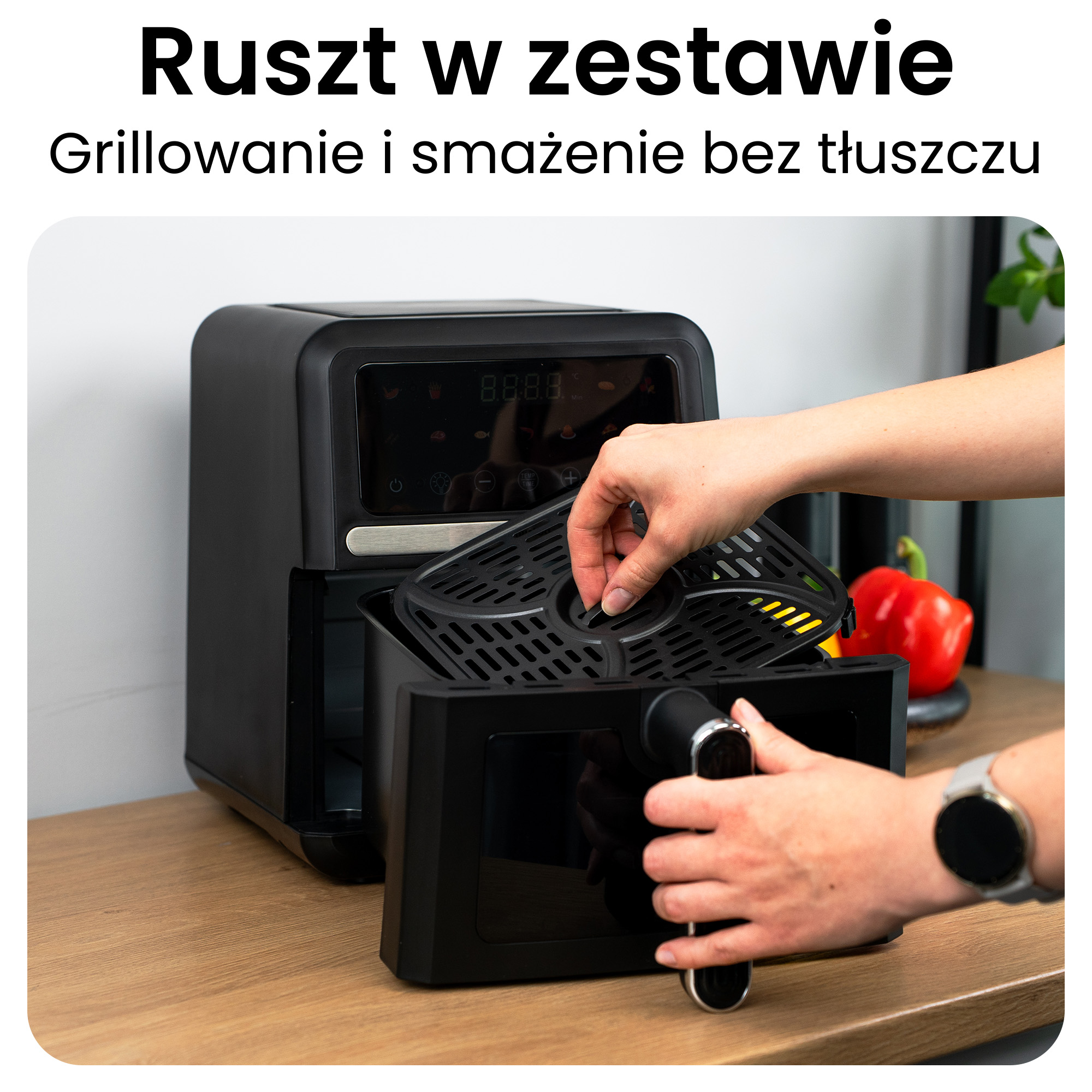 Ręka wkłada czarny kosz frytkownicy beztłuszczowej do urządzenia.