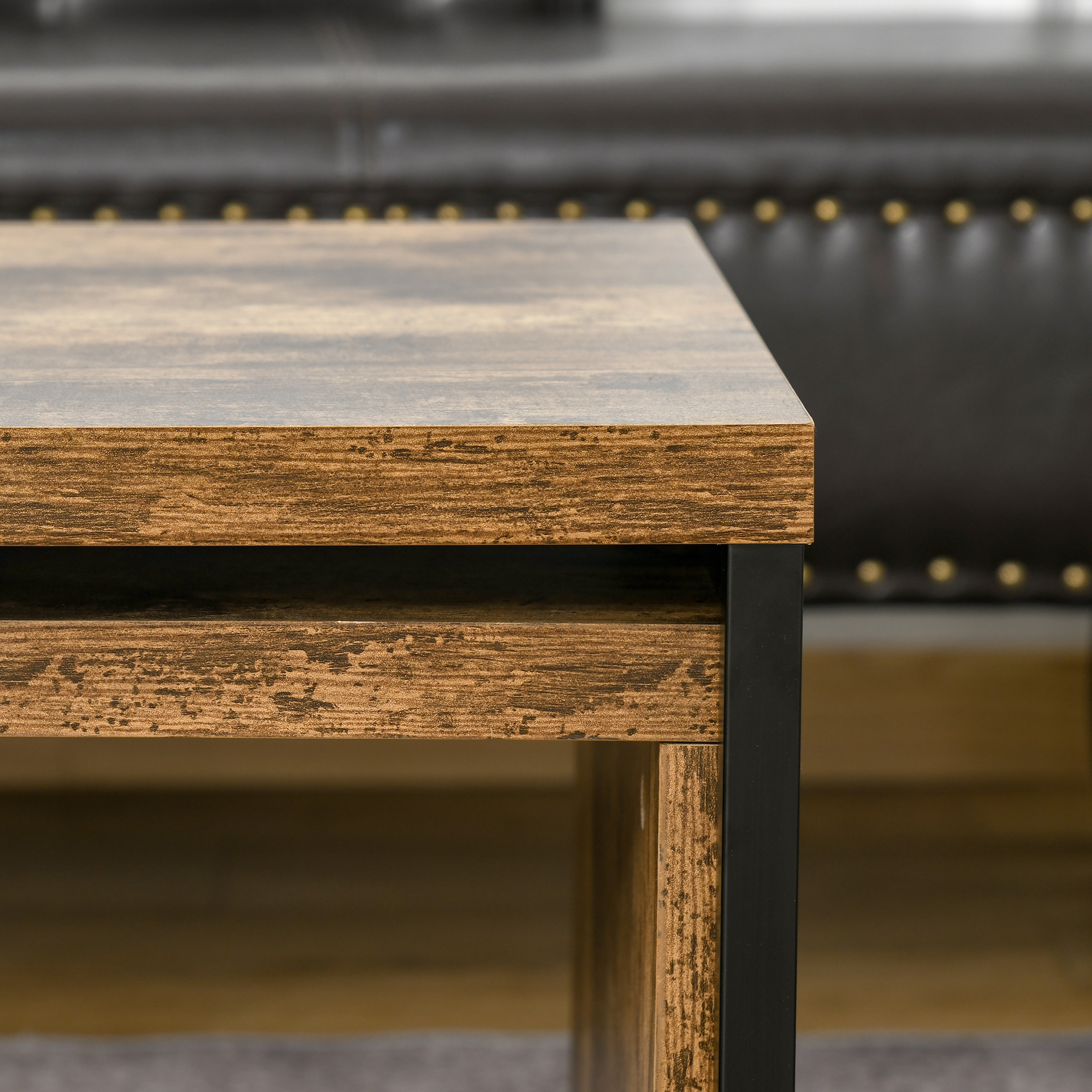 Mesa de madera con marco de metal negro y sofá con tachuelas al fondo.