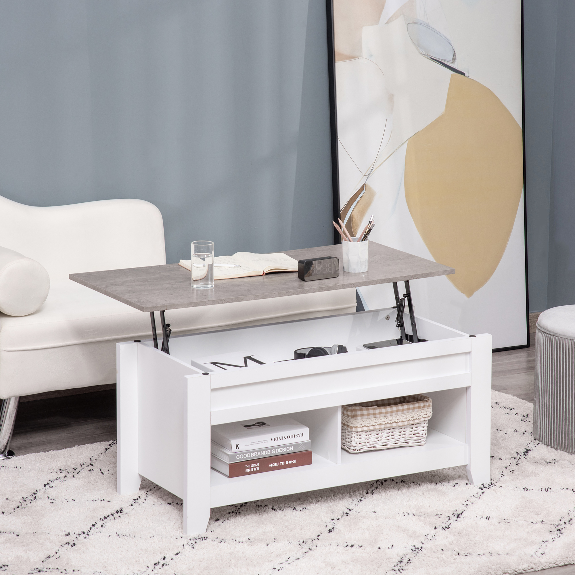 Mesa de centro elevable con tablero efecto hormigón, estante abierto, libros y cesta.