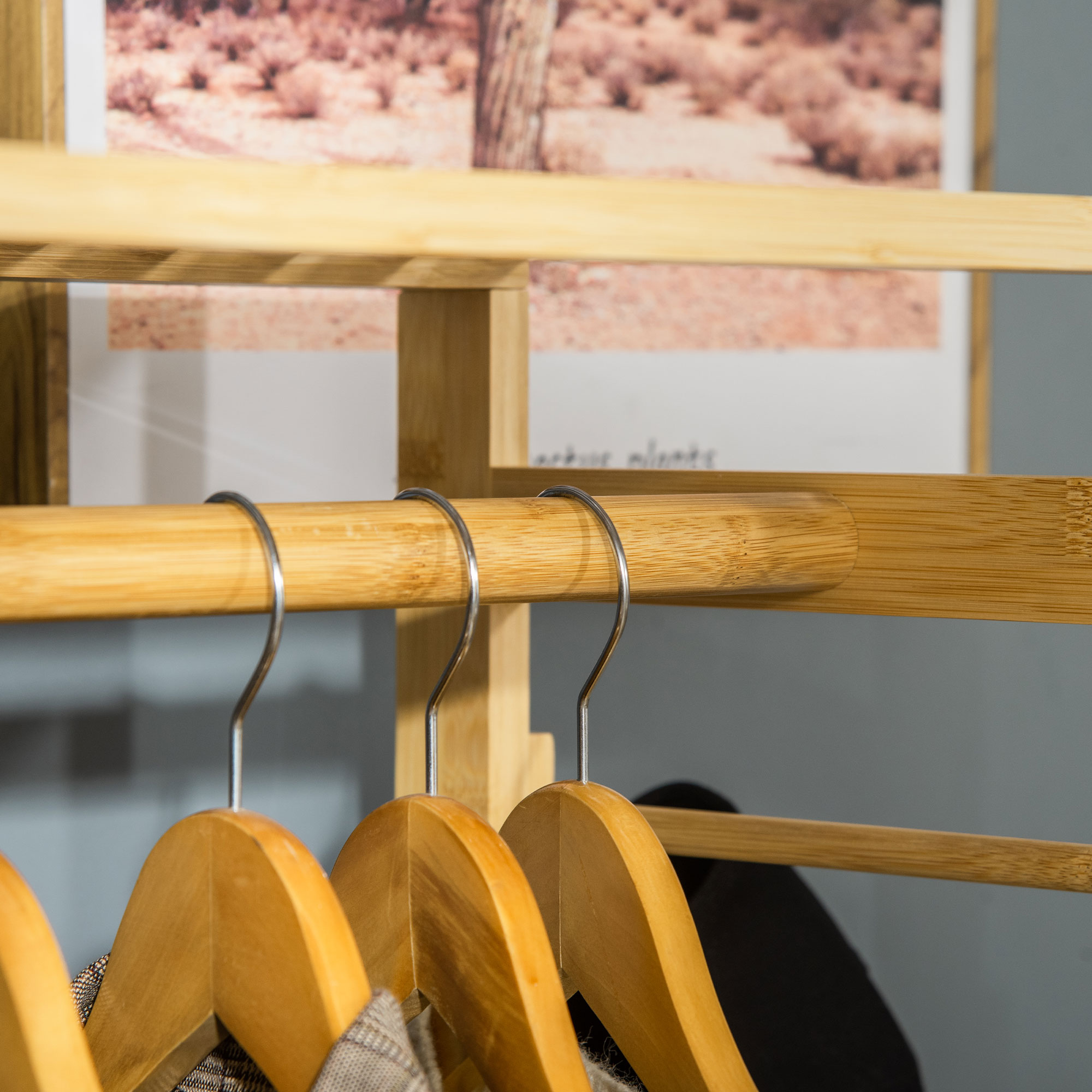 Perchero de madera con perchas y ropa. El fondo muestra un paisaje desértico.