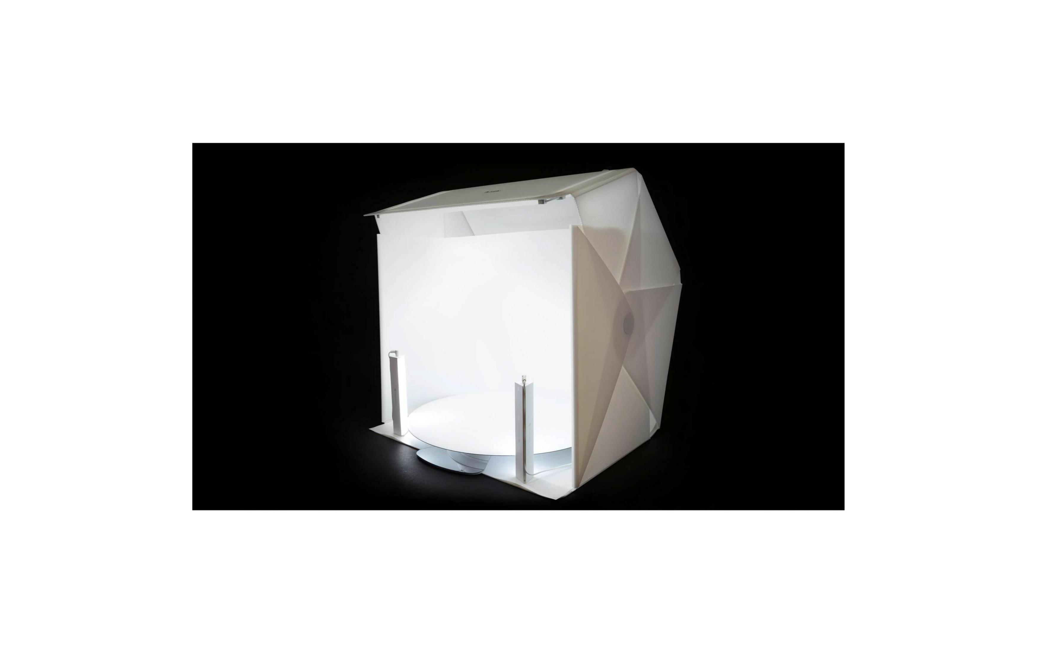 Una carpa blanca de estudio fotográfico con fondo negro y dos luces.