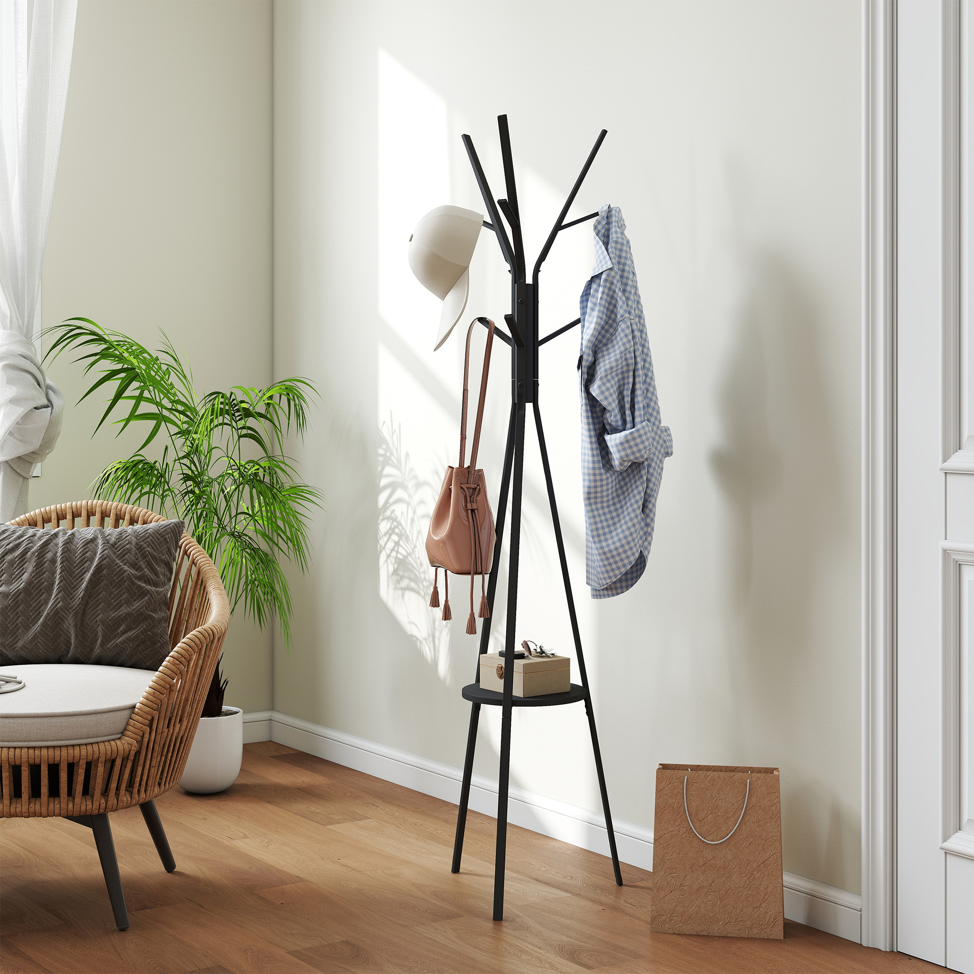Un perchero negro sostiene un sombrero, bolso y camisa, junto a un sillón de mimbre.