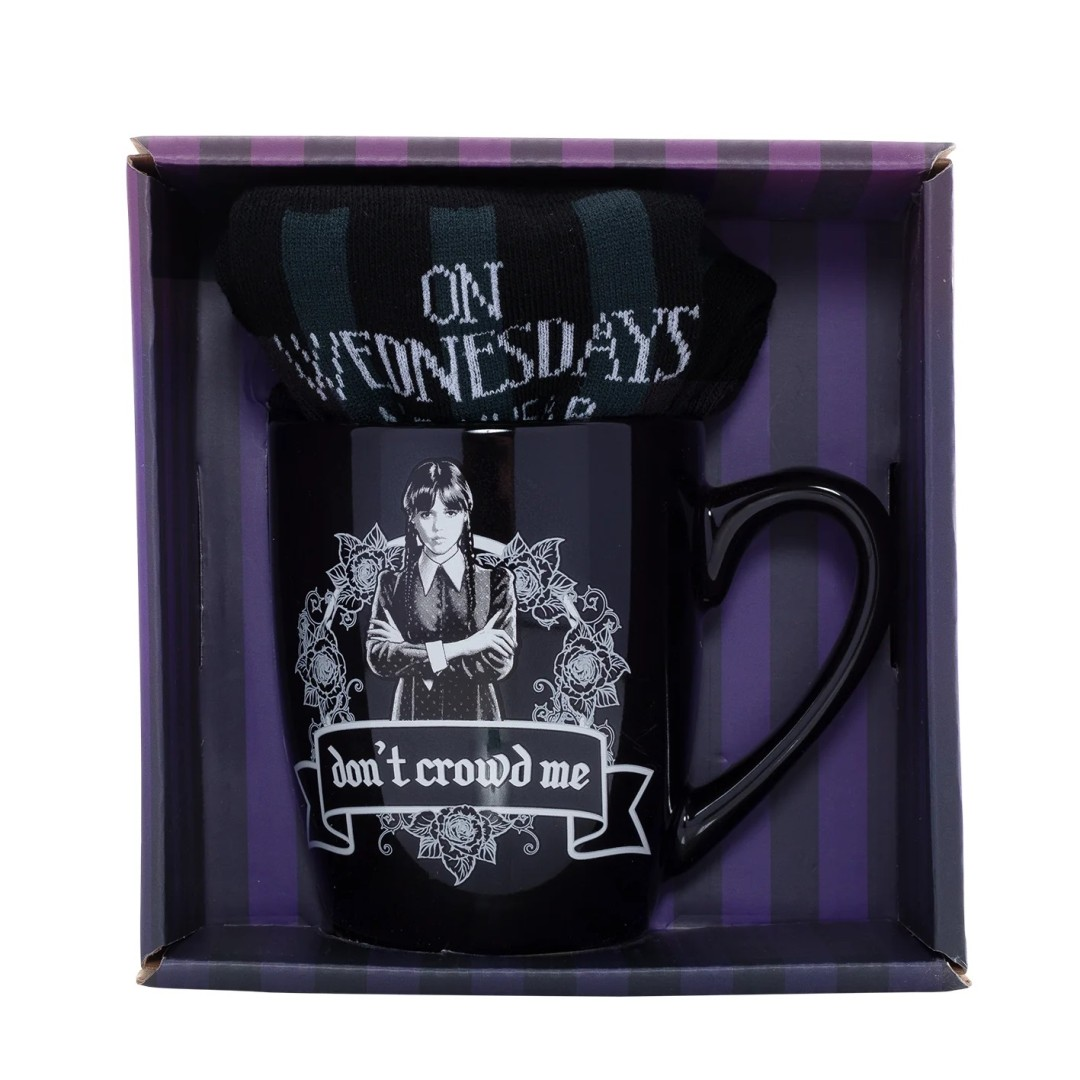 Czarny kubek z Wednesday Addams i pasującymi pasiastymi skarpetkami w pudełku.