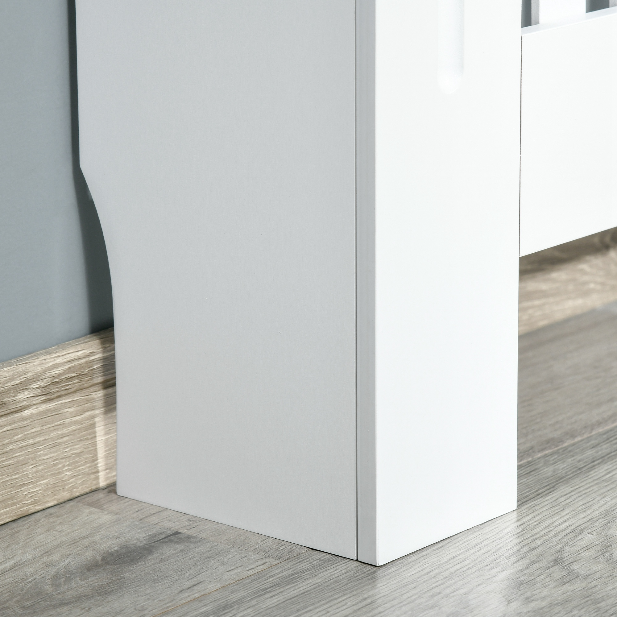 Borde de mueble blanco sobre suelo de madera gris y pared azul.