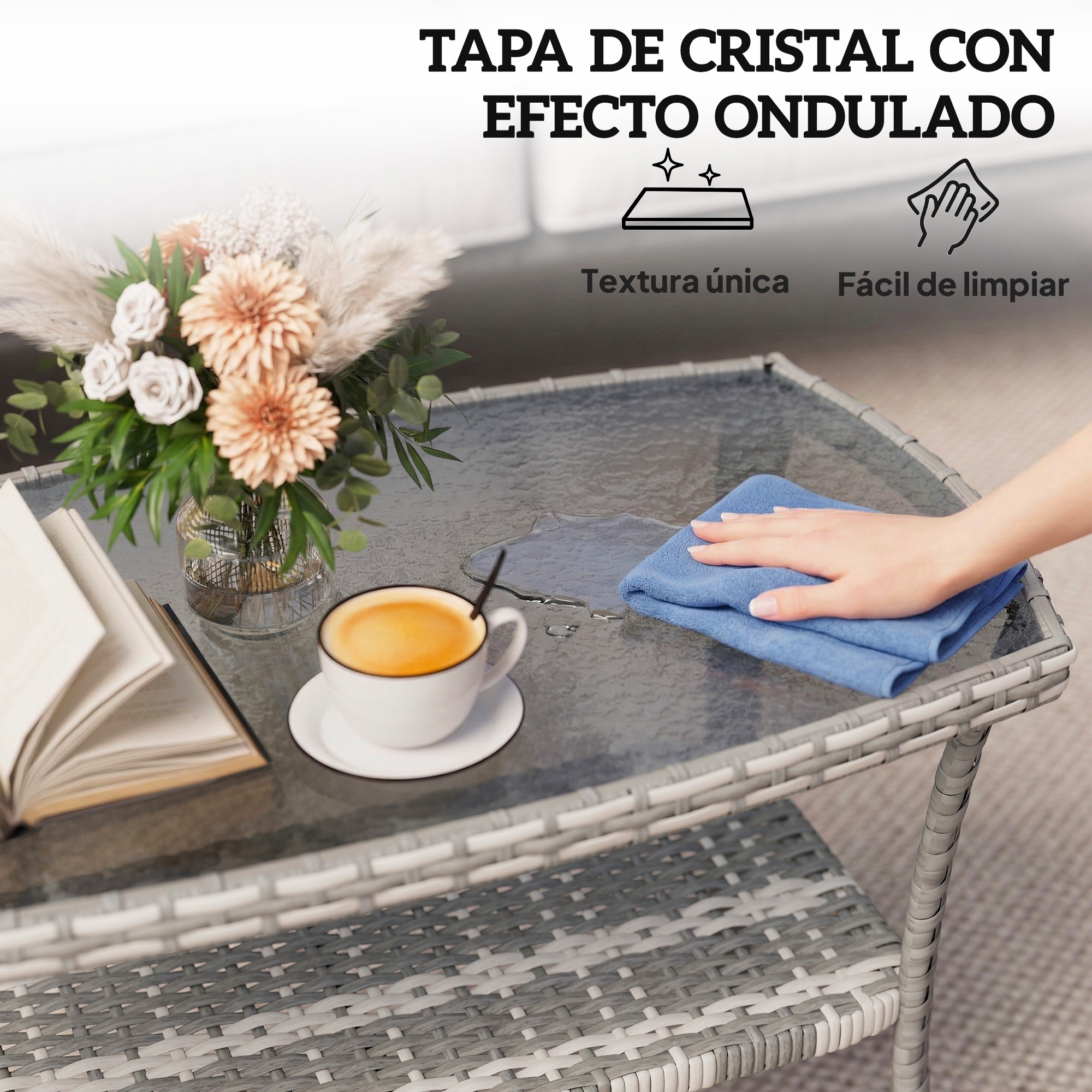 Una mesa con tapa de cristal, con una taza de café, un libro y un jarrón con flores.
