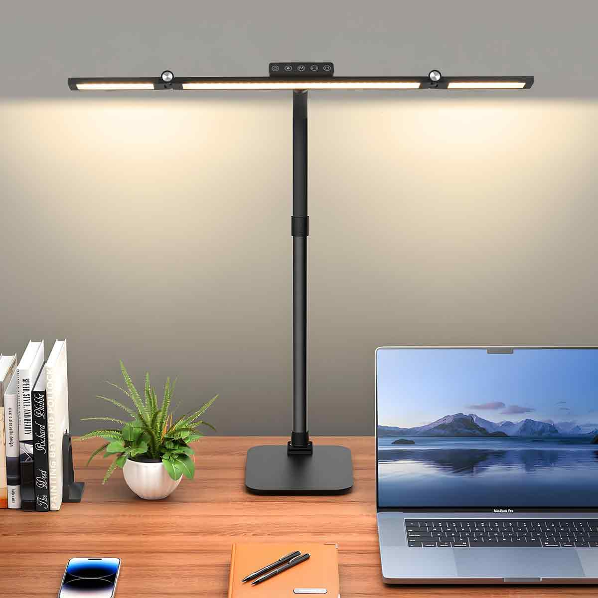 Ein Schreibtisch mit Lampe, Laptop, Büchern, Pflanze und Handy.