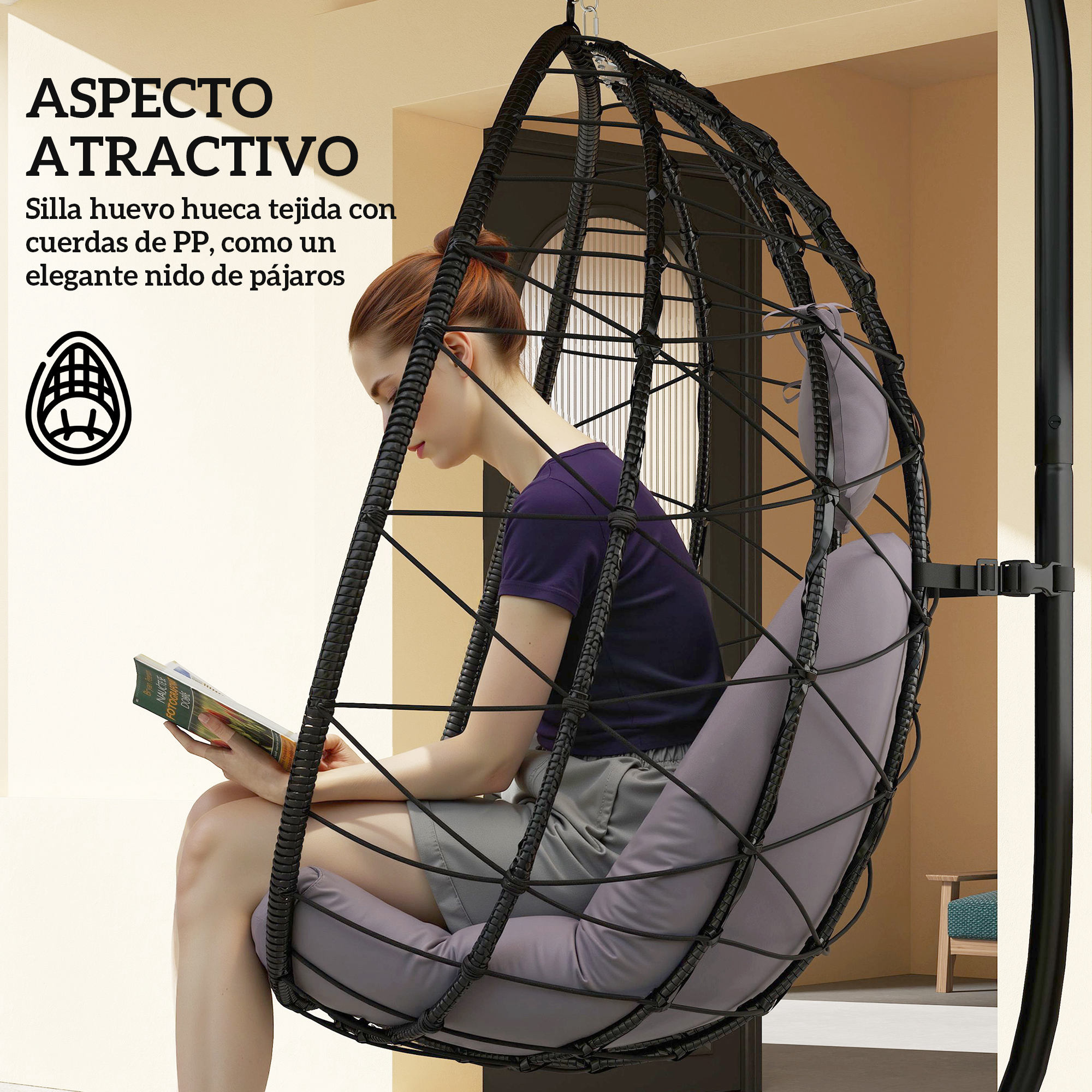 Una mujer lee un libro sentada en una silla colgante tejida negra.