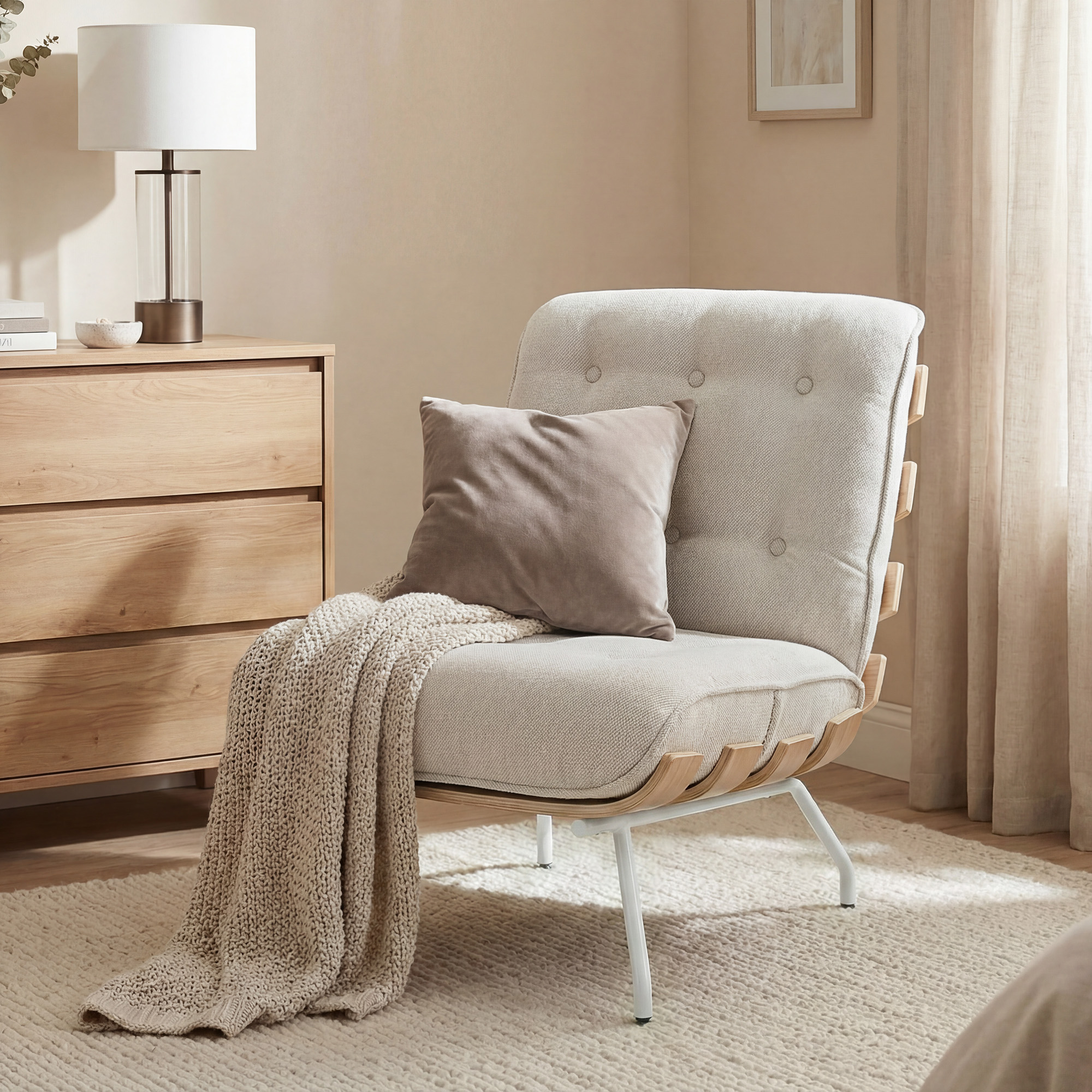 Un sillón beige con cojín y manta está sobre una alfombra junto a una cómoda.