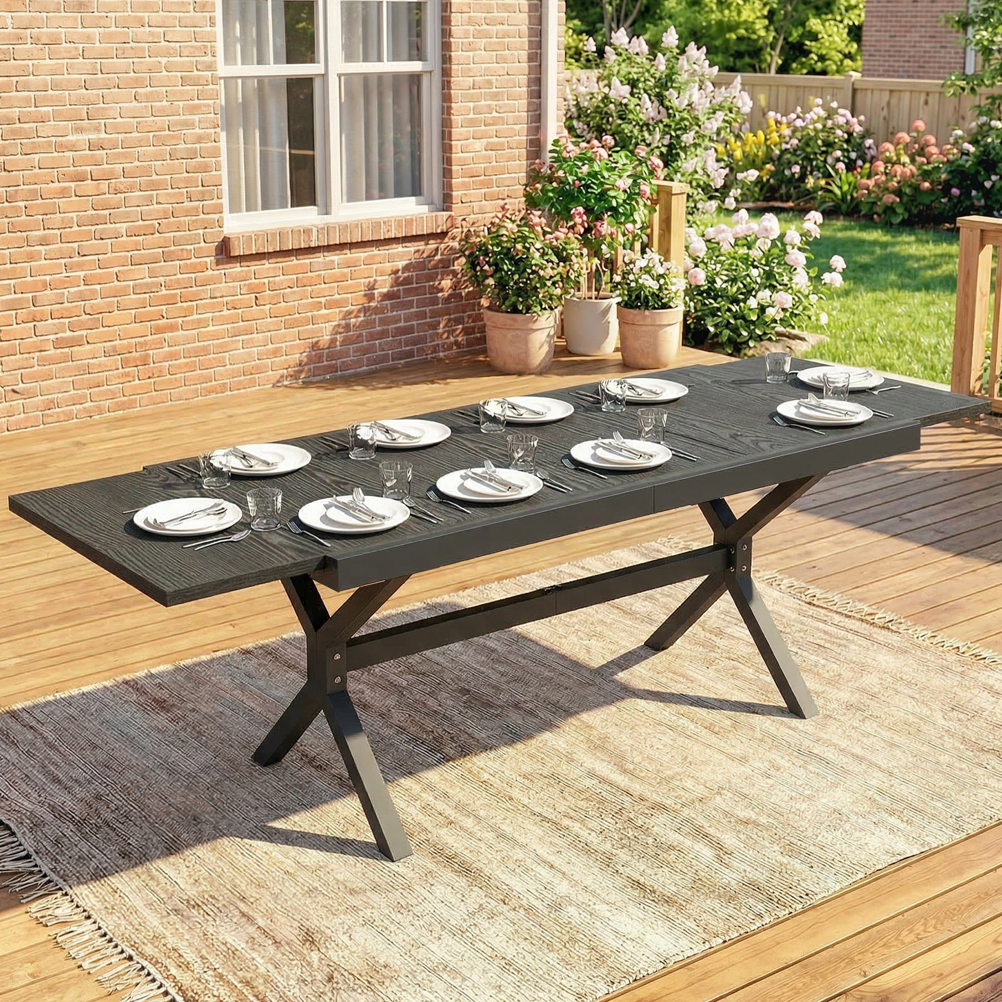 Mesa de comedor exterior para ocho personas en una terraza de madera con fondo de ladrillo.