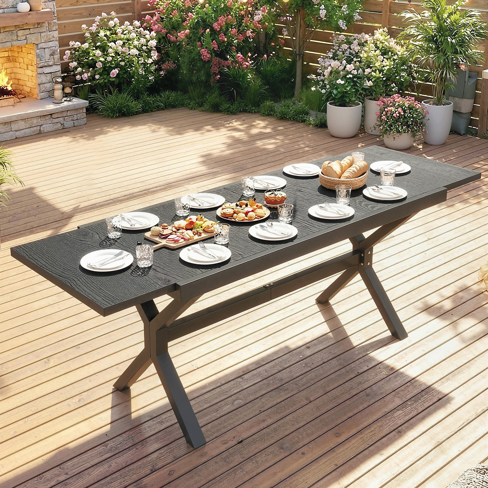 Una mesa de comedor al aire libre puesta con comida, bebidas y una chimenea al fondo.