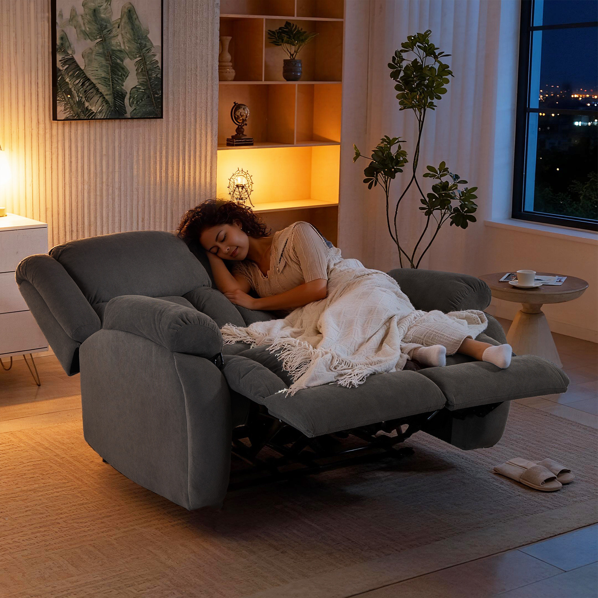 Una mujer duerme en un sillón reclinable oscuro, cubierta con una manta.