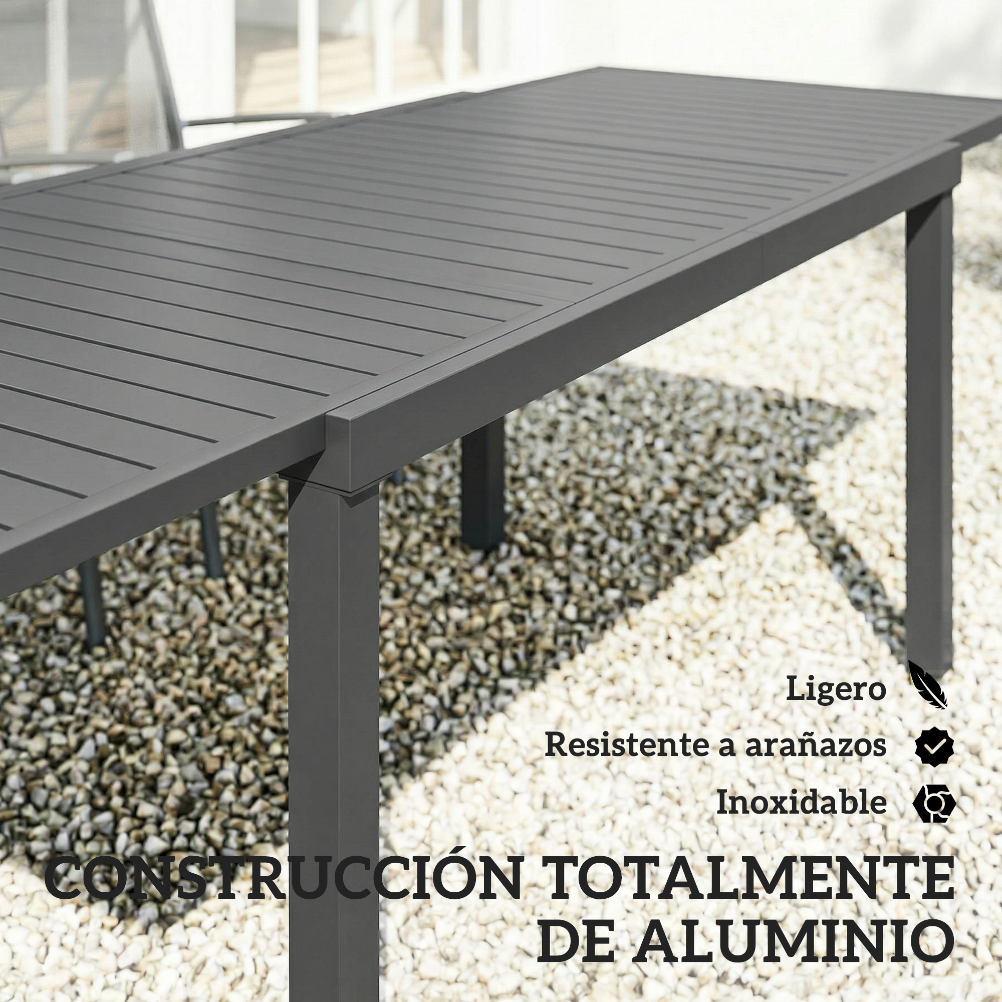 Mesa gris de aluminio con superficie de listones sobre grava.