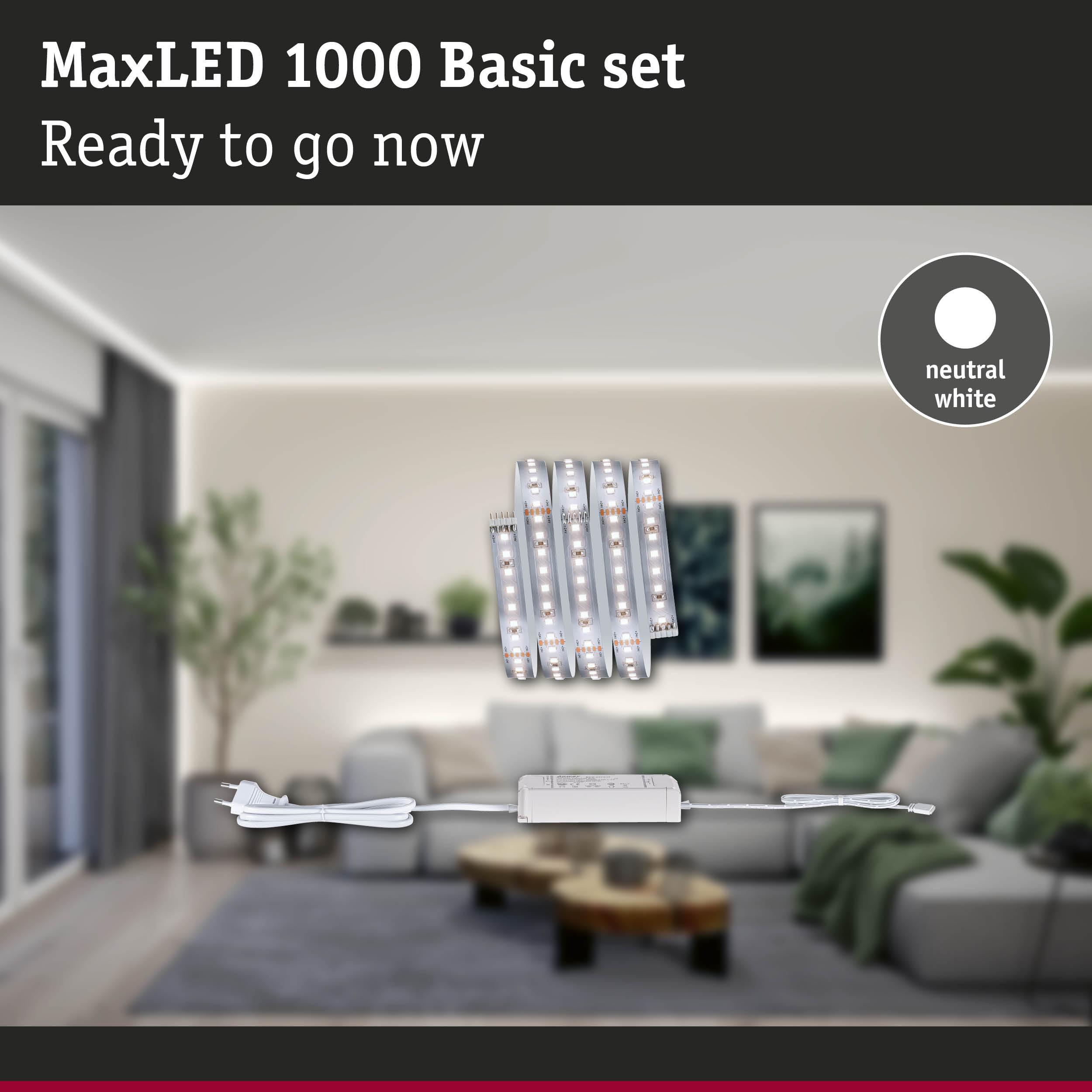 Vier LED-Streifen mit Netzteil und Stecker auf einem Teppich vor einem Sofa.