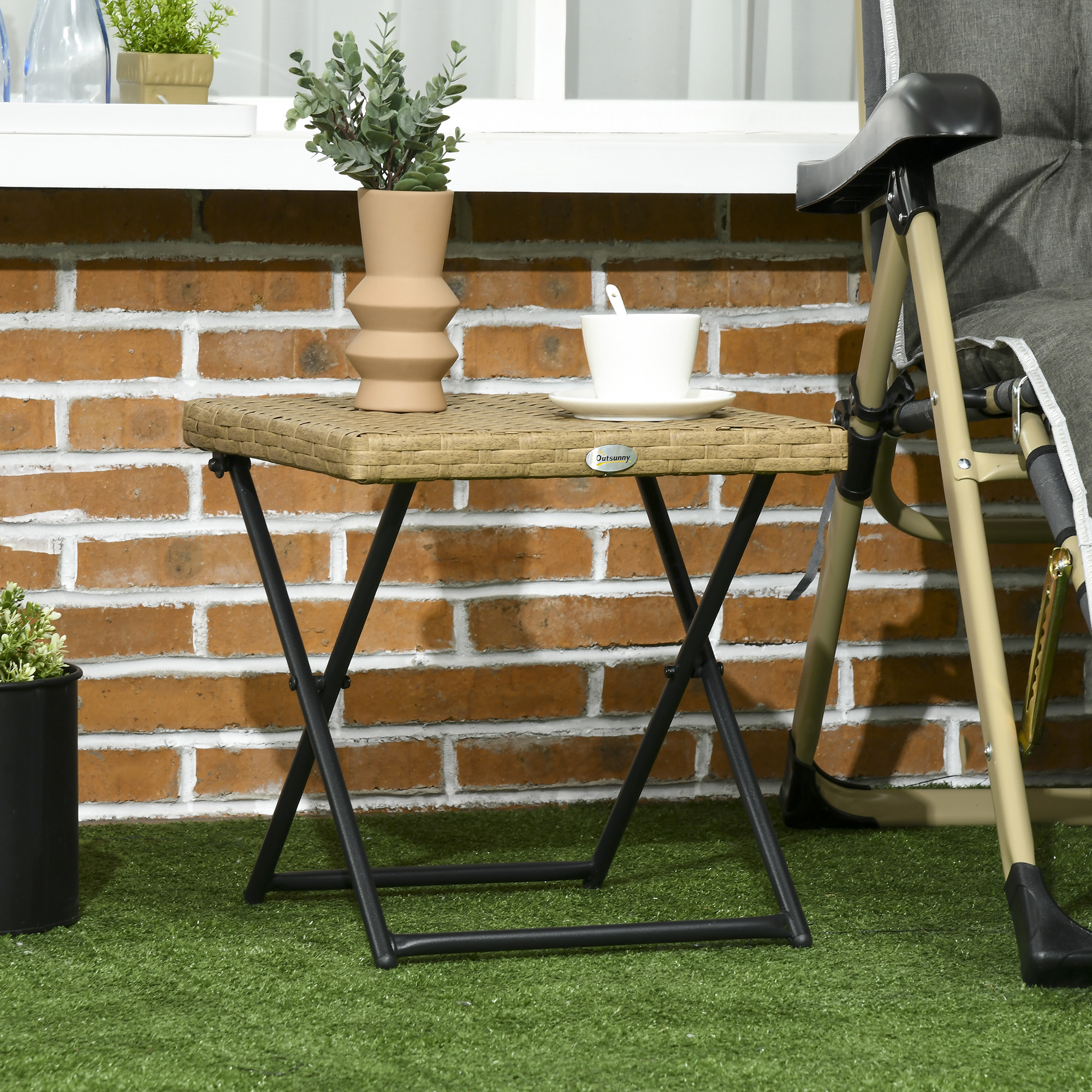 Un tavolino effetto rattan con tazza e pianta su sfondo di mattoni.