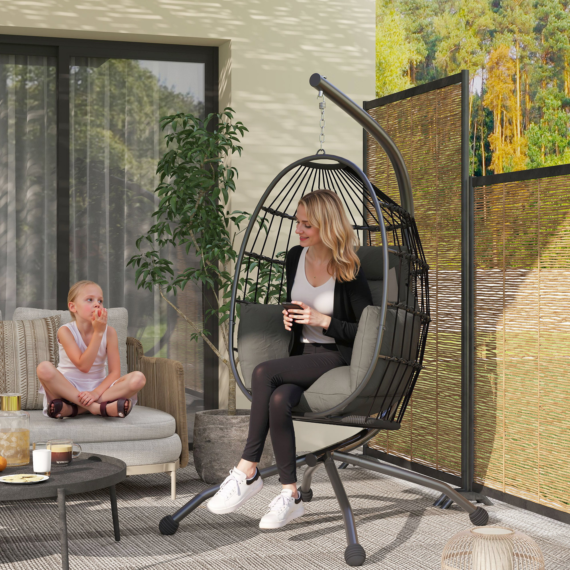 Donna e bambino su un patio con sedia sospesa e divano.