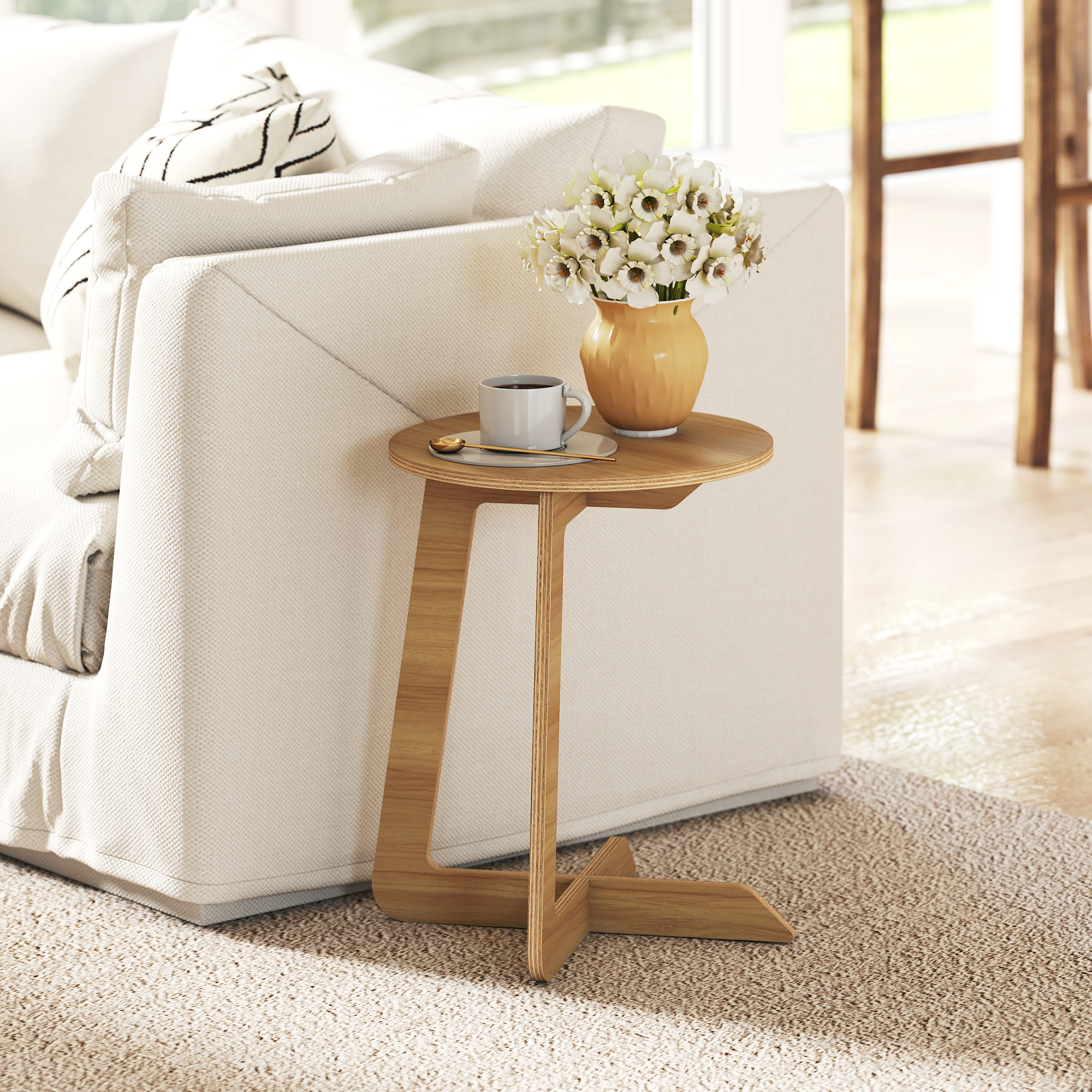 Una mesa auxiliar de madera junto a un sofá blanco con un jarrón de flores y una taza de café.