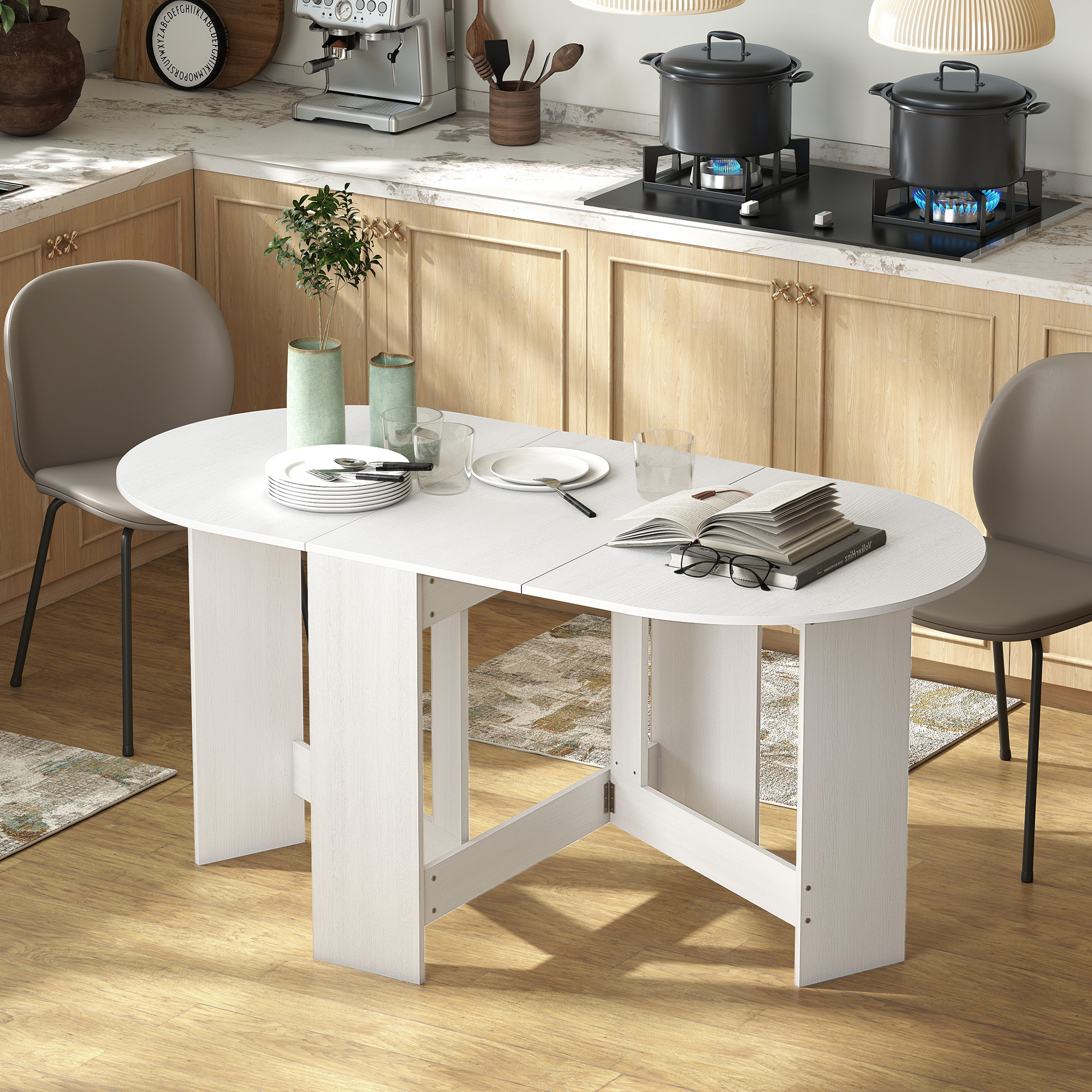 Una mesa ovalada blanca puesta para dos, con platos, vasos y un libro abierto.
