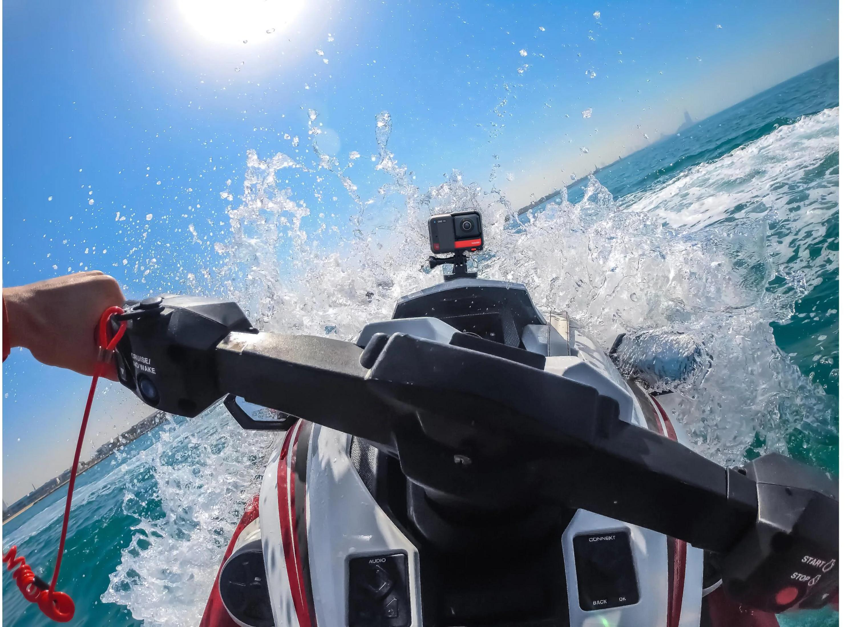 Hand am Jet-Ski-Lenker, Wasser spritzt, Kamera auf dem Steuer.