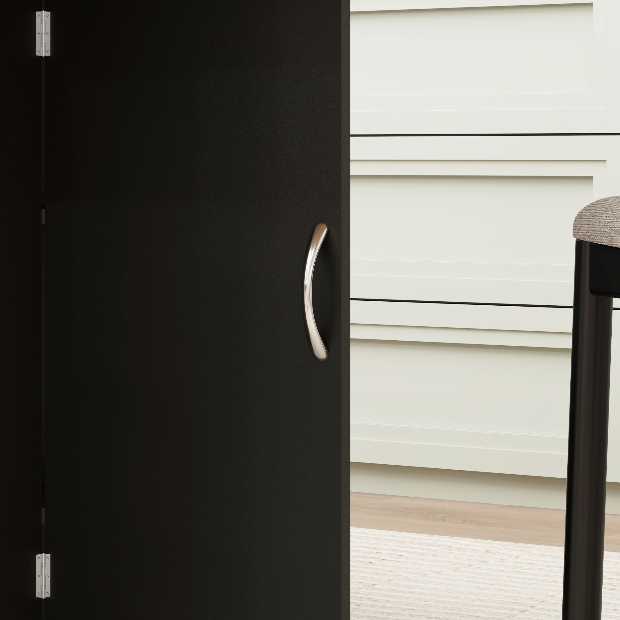 Puerta negra con tirador plateado, junto a cajones blancos y un taburete.