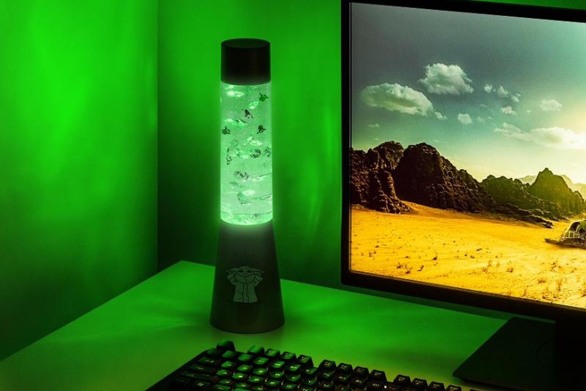 Zielona lampa z Baby Yodą i monitor z pustynnym krajobrazem.