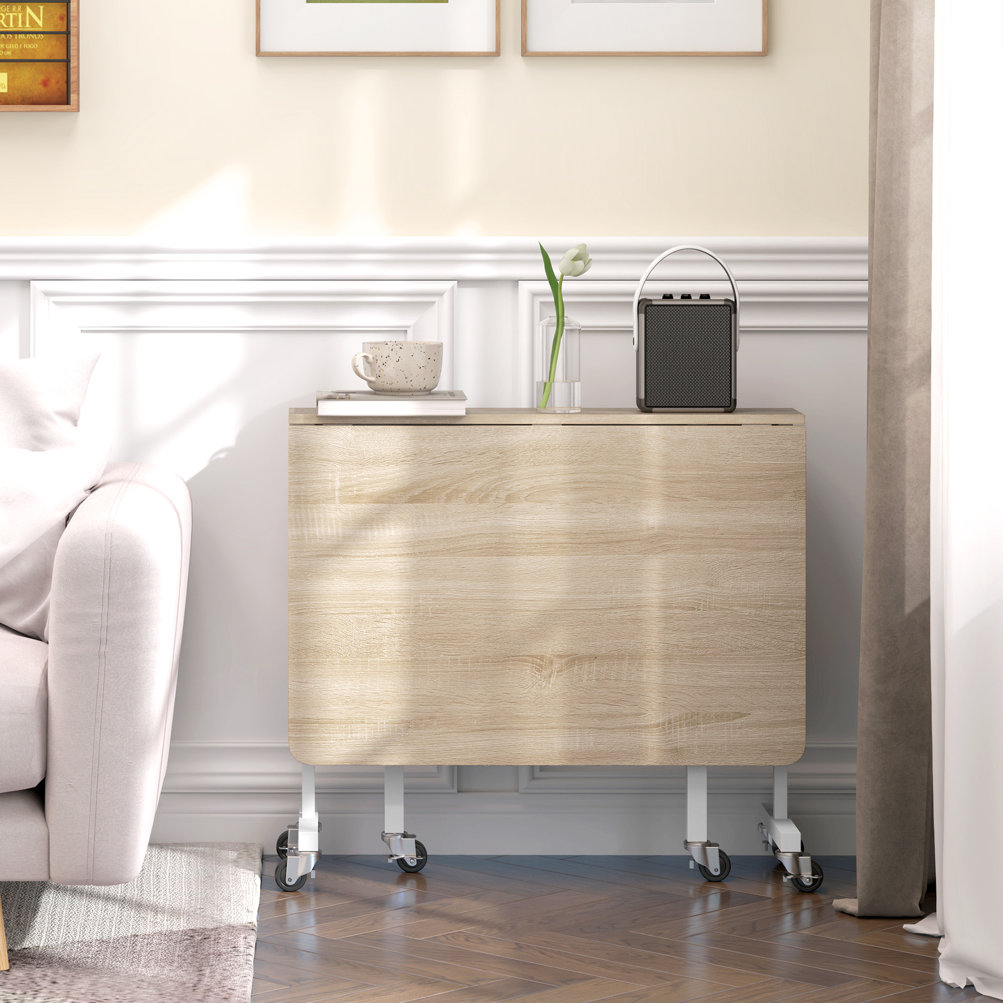 Una mesa plegable de madera con ruedas junto a un sofá. Encima hay una taza, un libro y un altavoz.