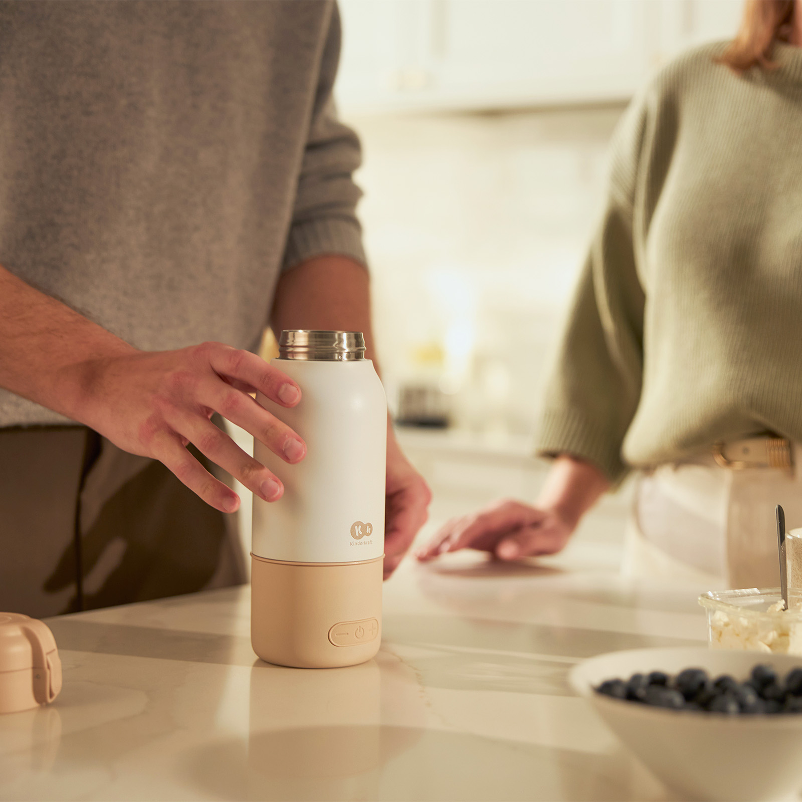 Eine weiße und beige Thermoskanne wird auf einer Arbeitsplatte gehalten.