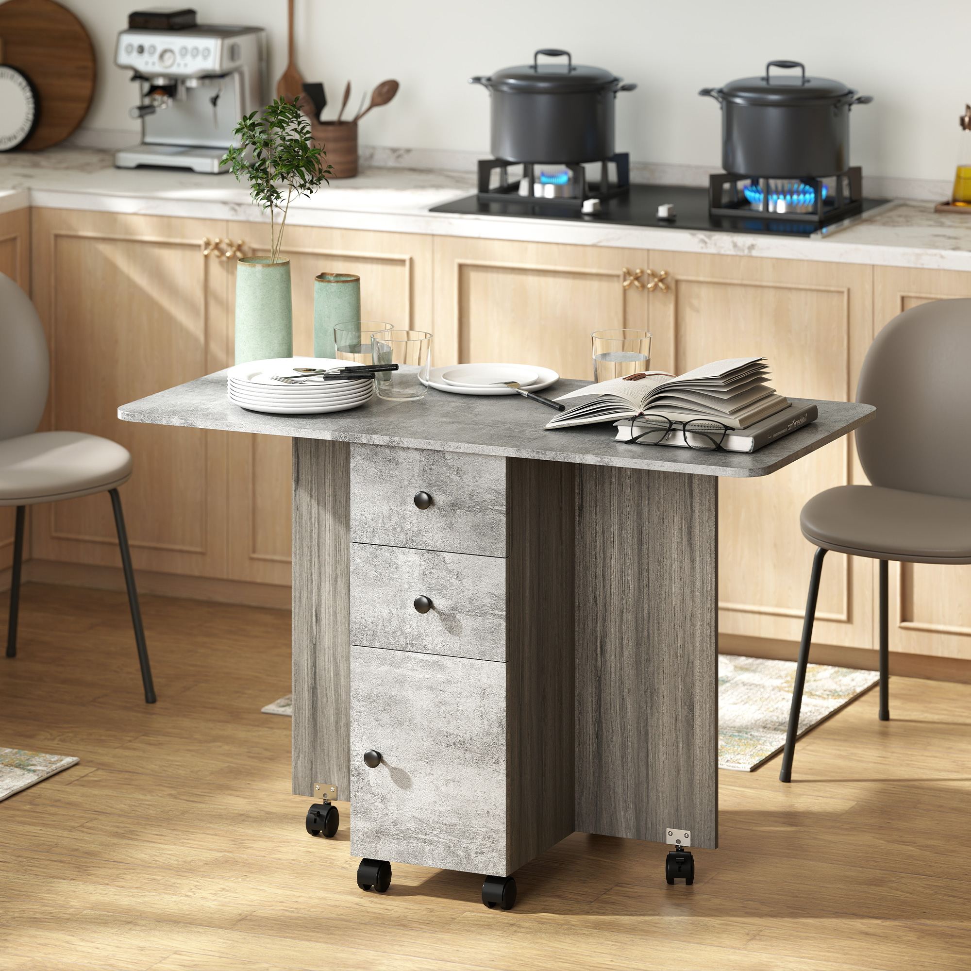 Una mesa plegable gris con cajones, puesta para comer, con sillas y cocina al fondo.