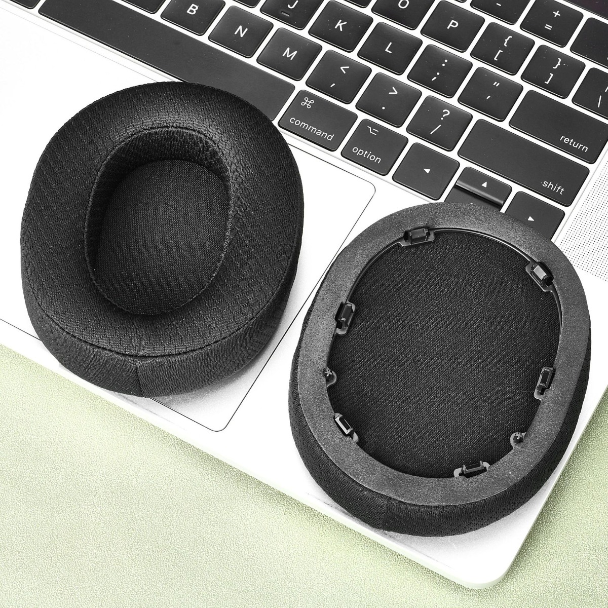 Cuscinetti neri per cuffie appoggiati sulla tastiera di un laptop.
