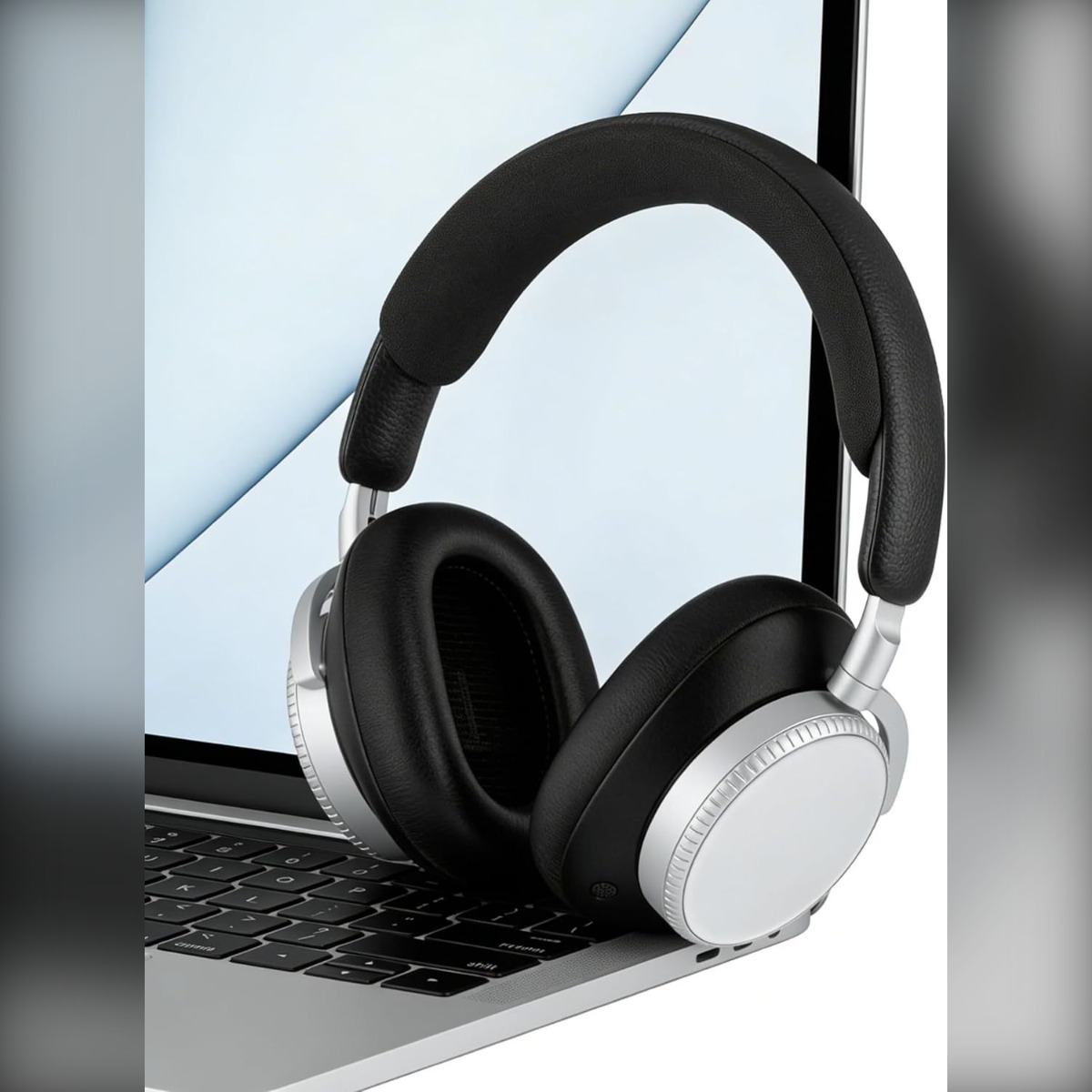 Schwarze Kopfhörer mit silbernen Akzenten liegen auf einer Laptop-Tastatur.