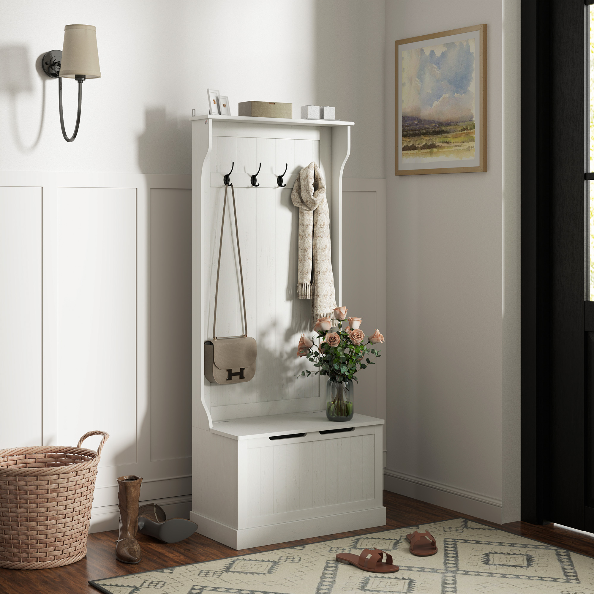 Un mueble de recibidor blanco con ganchos, bolso, bufanda, flores y banco.