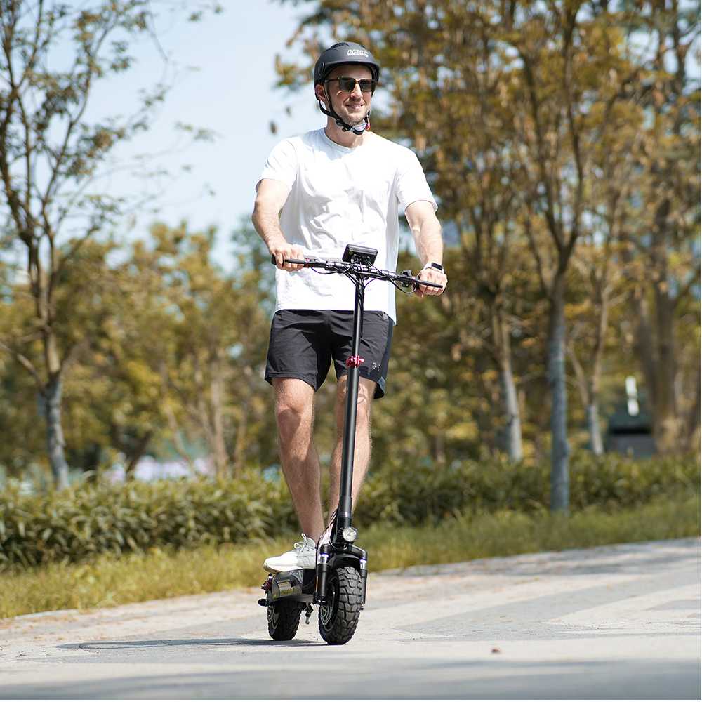 Un uomo guida un monopattino elettrico nero su un sentiero del parco.