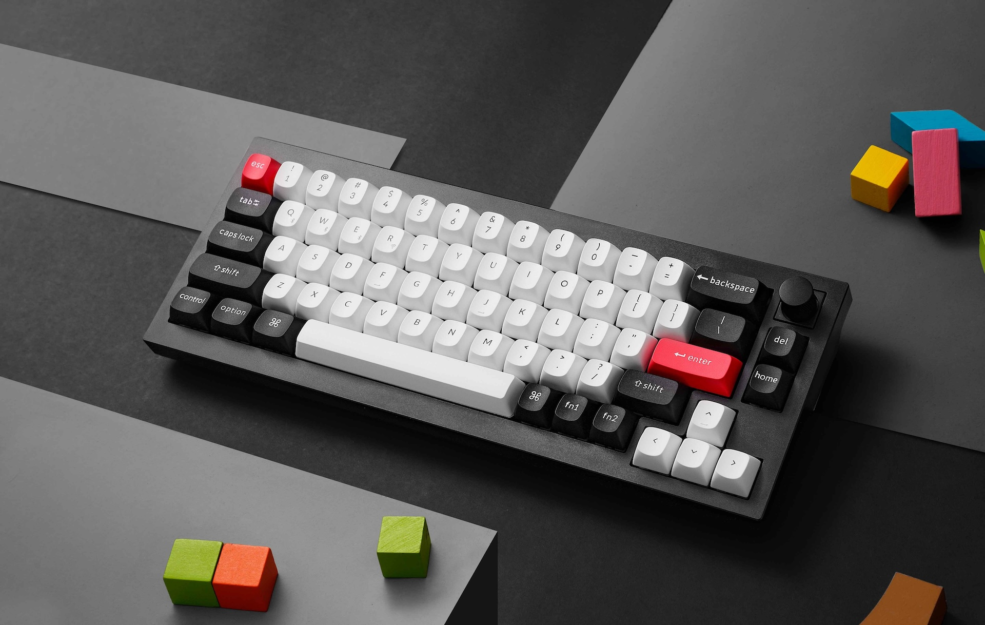 Czarna klawiatura mechaniczna z białymi i czerwonymi klawiszami leży na ciemnej powierzchni.