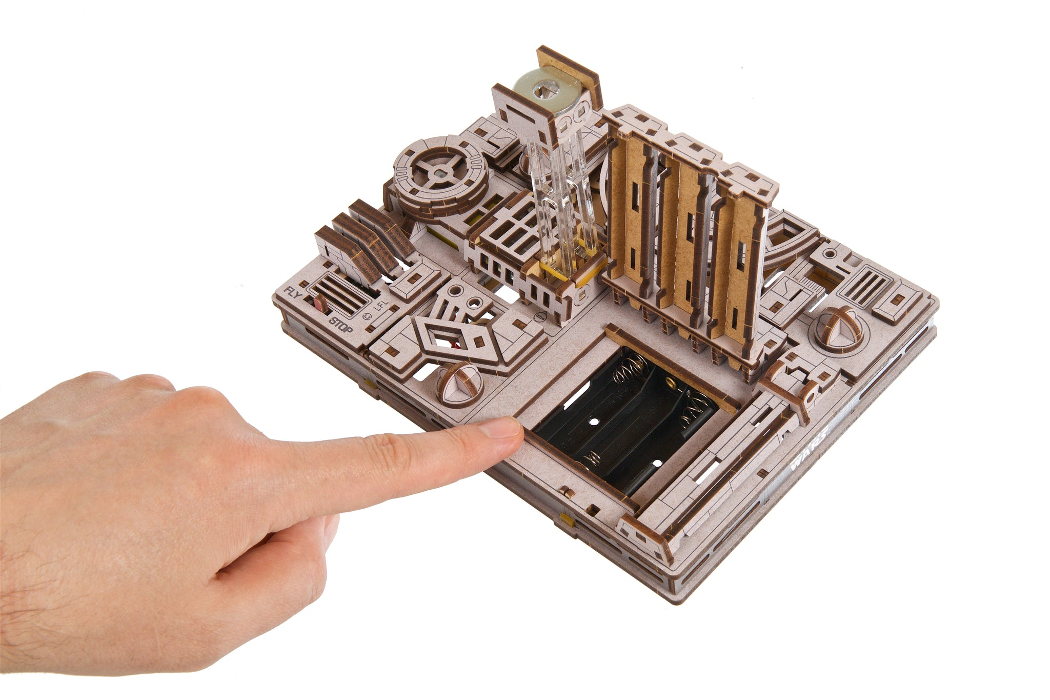 Ein Finger zeigt auf ein Holzmodell mit Batteriefach und komplizierten Details.