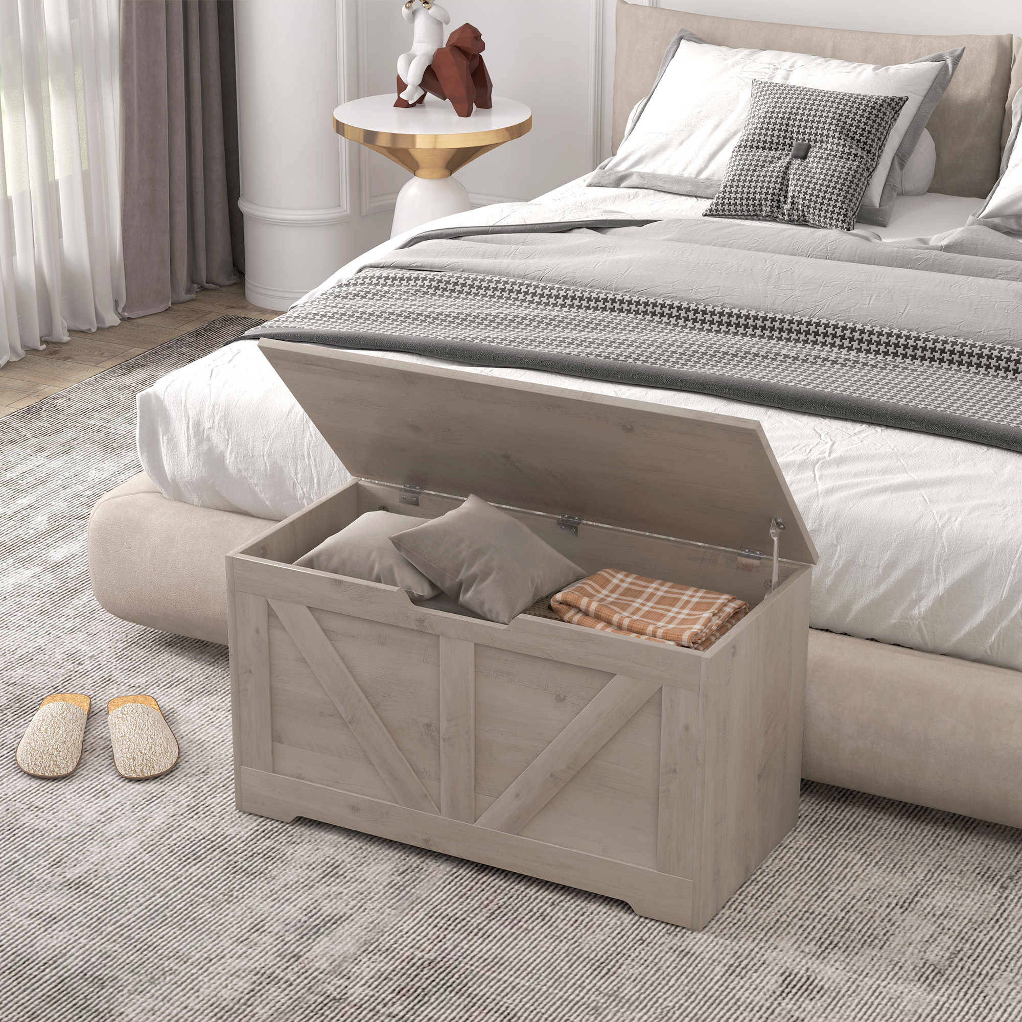 Un baúl de madera abierto con cojines y manta junto a una cama.